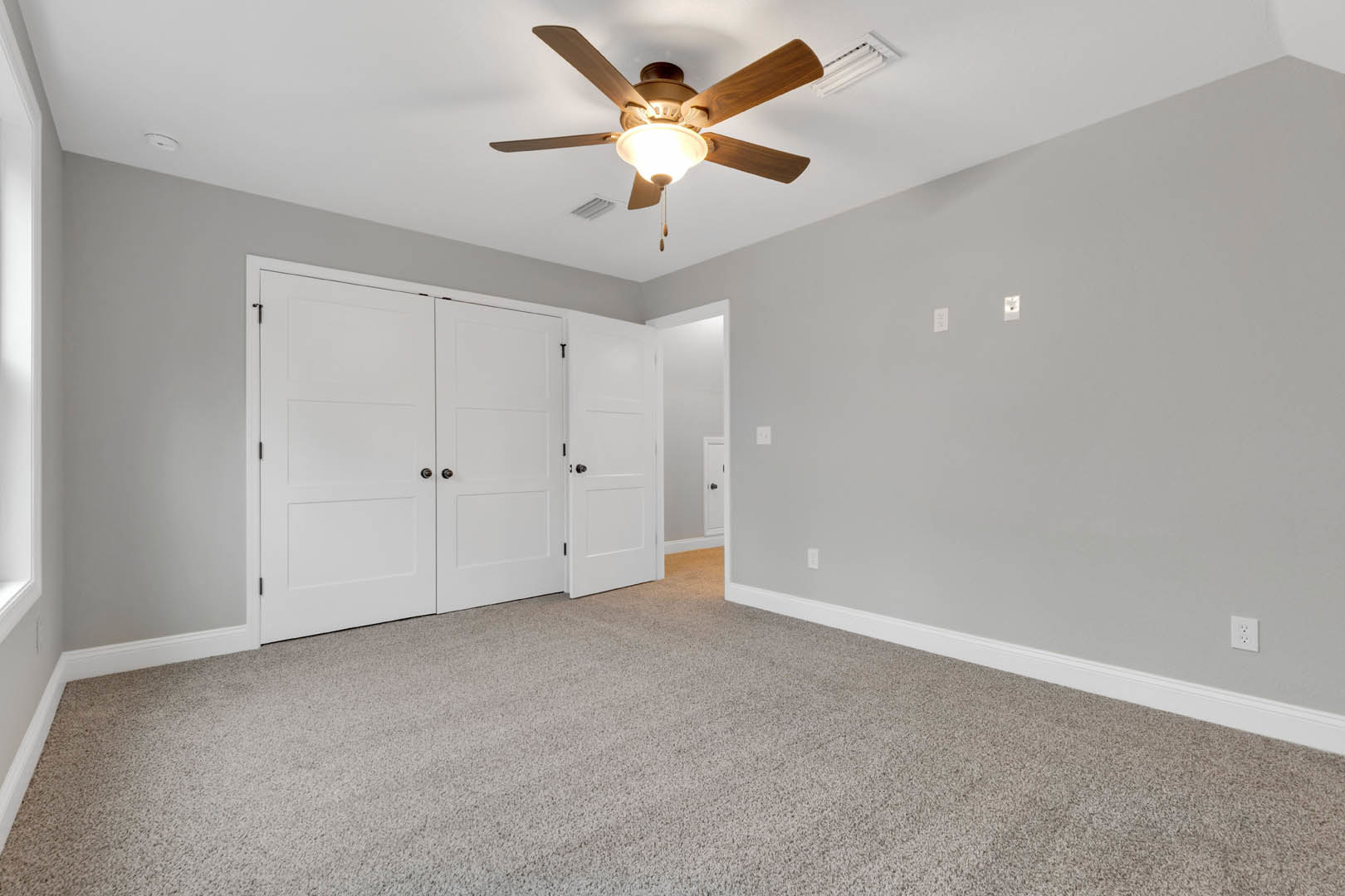 Carpeted room with white walls, ceiling fan with light, white door featuring black handle, and plaster ceiling
