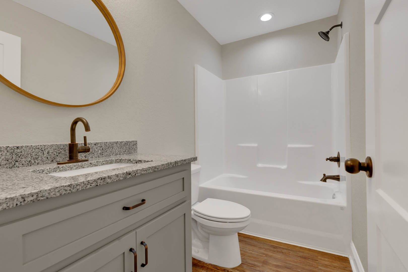 Modern bathroom featuring white ceramic sink with chrome faucet, wall-mounted mirror above, adjacent toilet, tiled walls and floor, built-in cabinet with metal handles, and exposed
