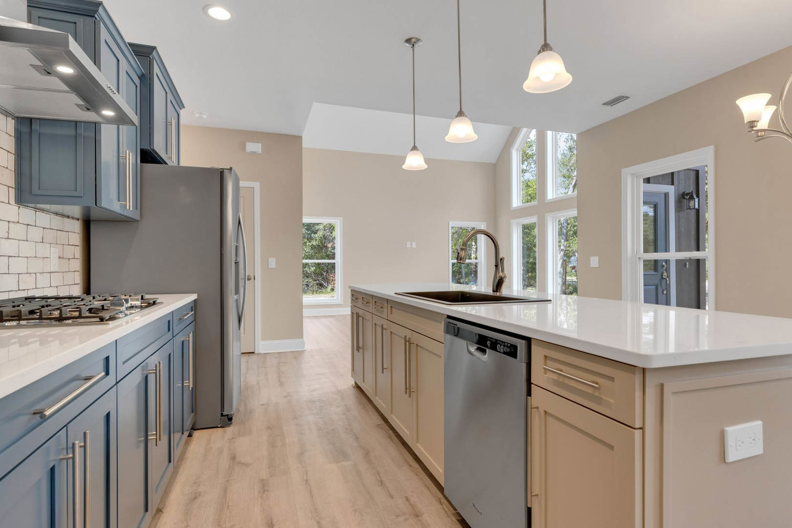Kitchen featuring stainless steel refrigerator and dishwasher, white cabinetry, stone countertops, stainless steel sink with modern faucet, white walls, electrical outlet, window