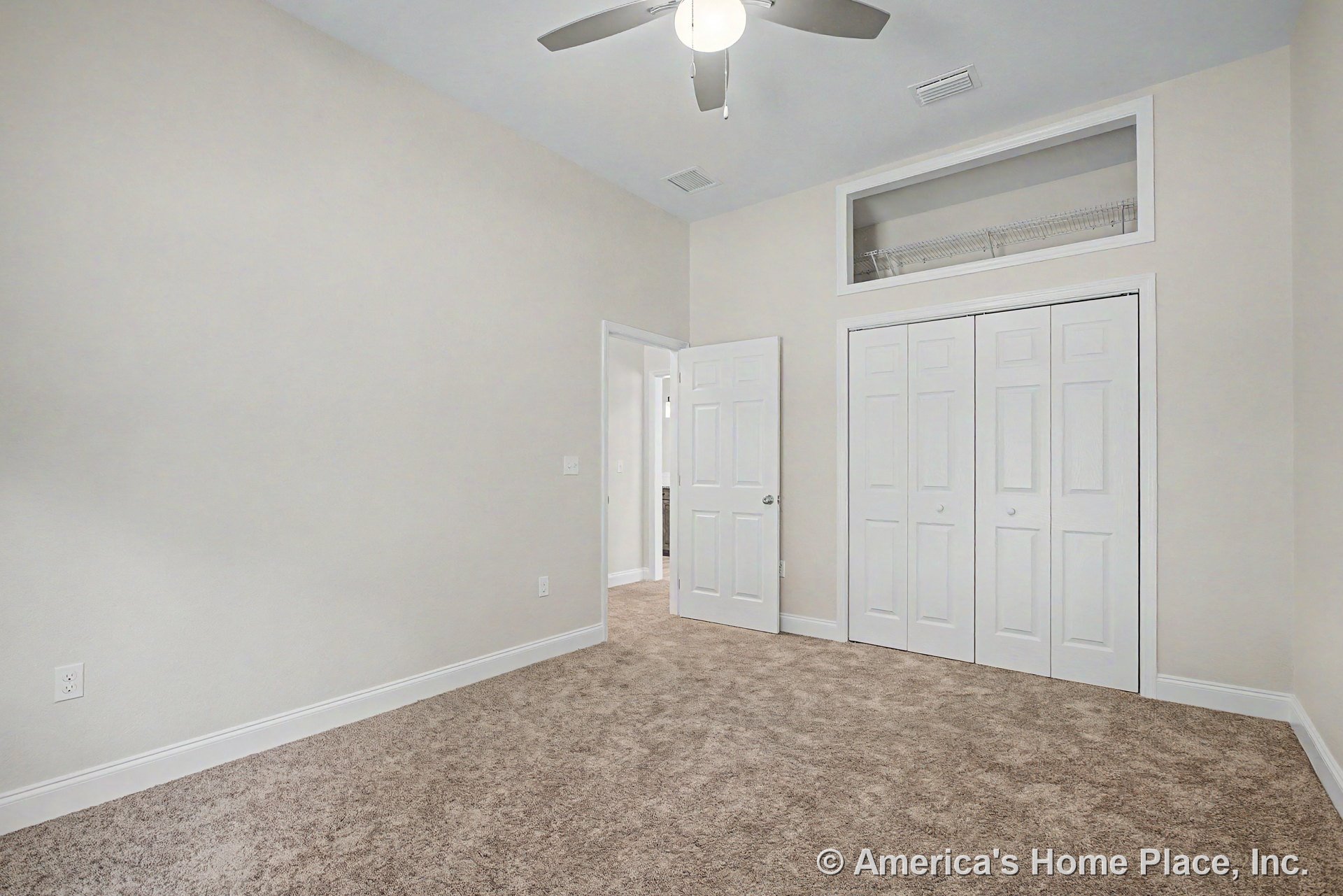 Carpeted bedroom with double white closet doors, ceiling fan and light fixture, neutral wall color, white baseboard trim, and upper closet shelf.