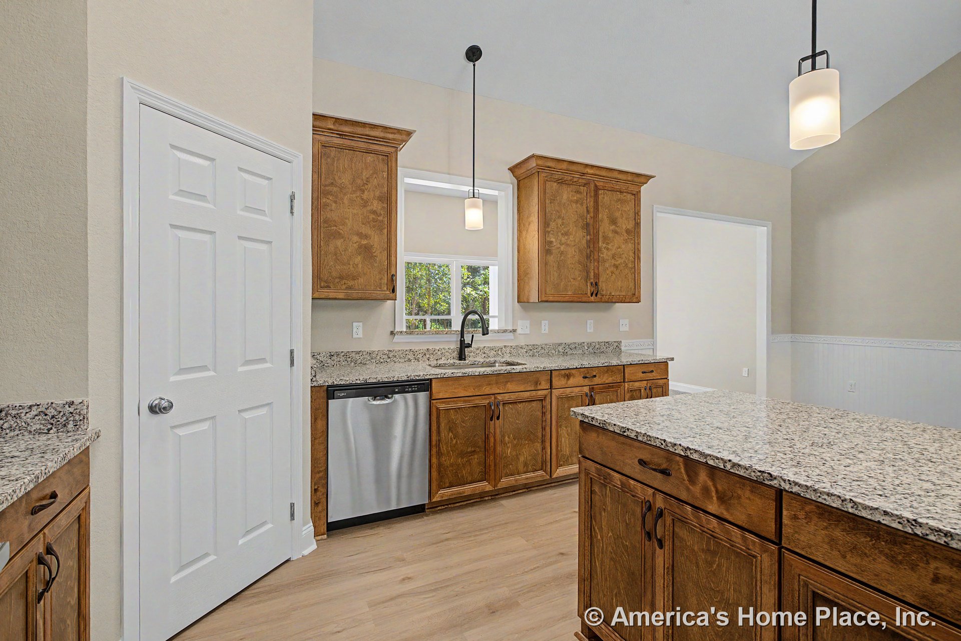 Granite kitchen island with wood upper and lower cabinets, stainless steel dishwasher, pendant ceiling lights, double window above sink, light wood flooring, and pantry door with