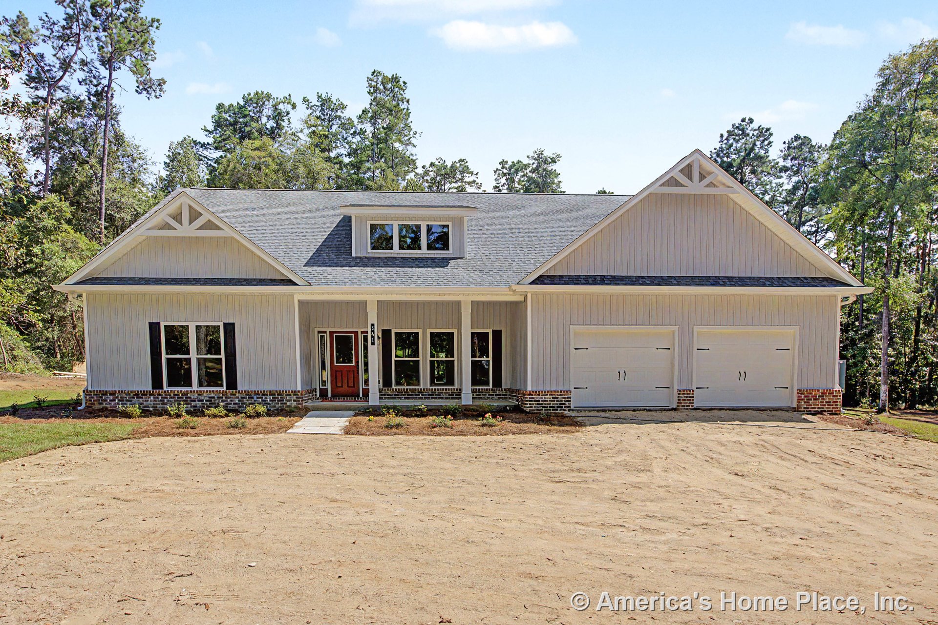 Covered front porch with brick foundation trim, double garage doors, vertical siding, large front windows, gable roof featuring decorative trusses, and prominent front door.