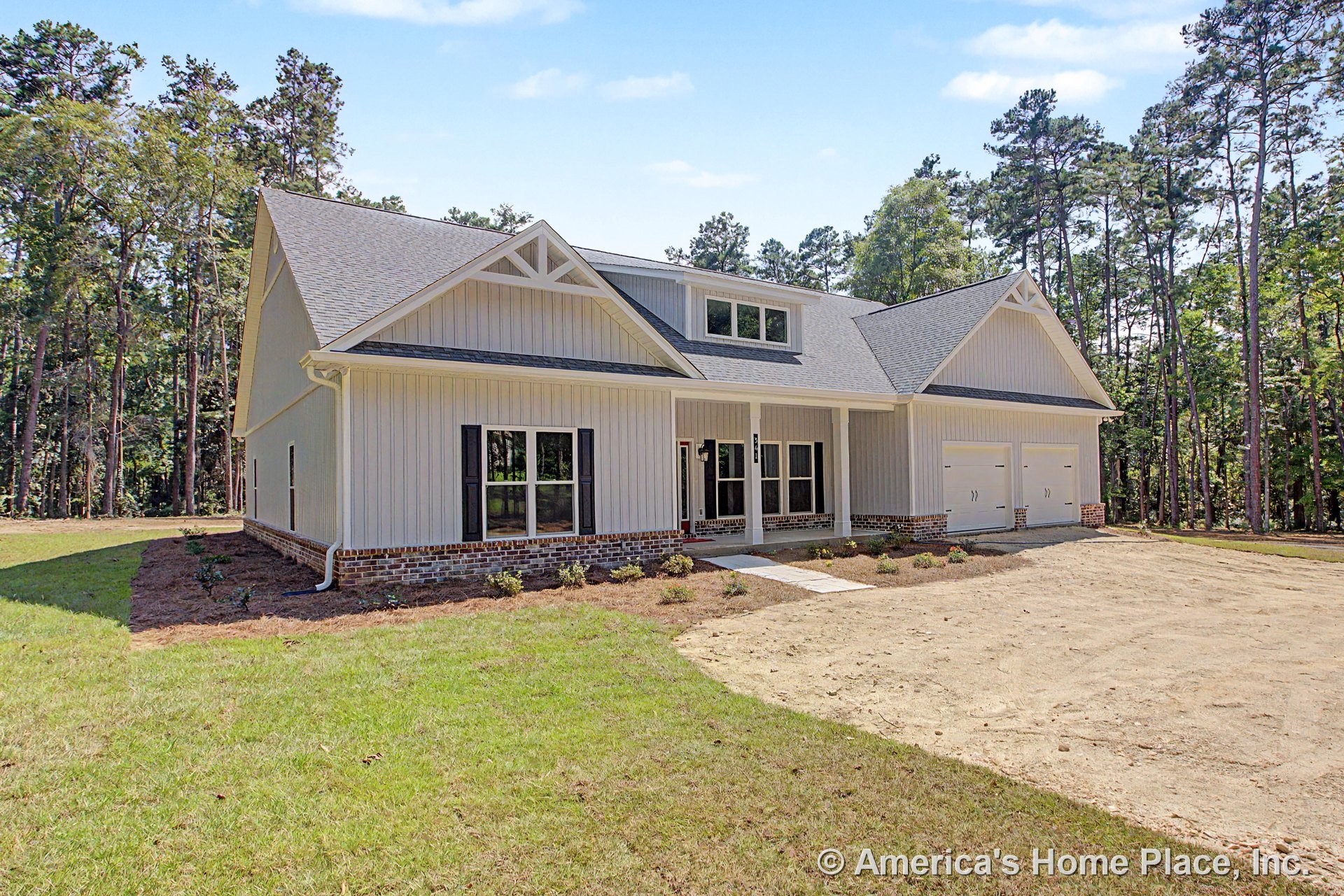 Vertical board and batten siding with brick foundation trim, covered front porch supported by columns, double garage doors, black window shutters, gable roof featuring a decorative