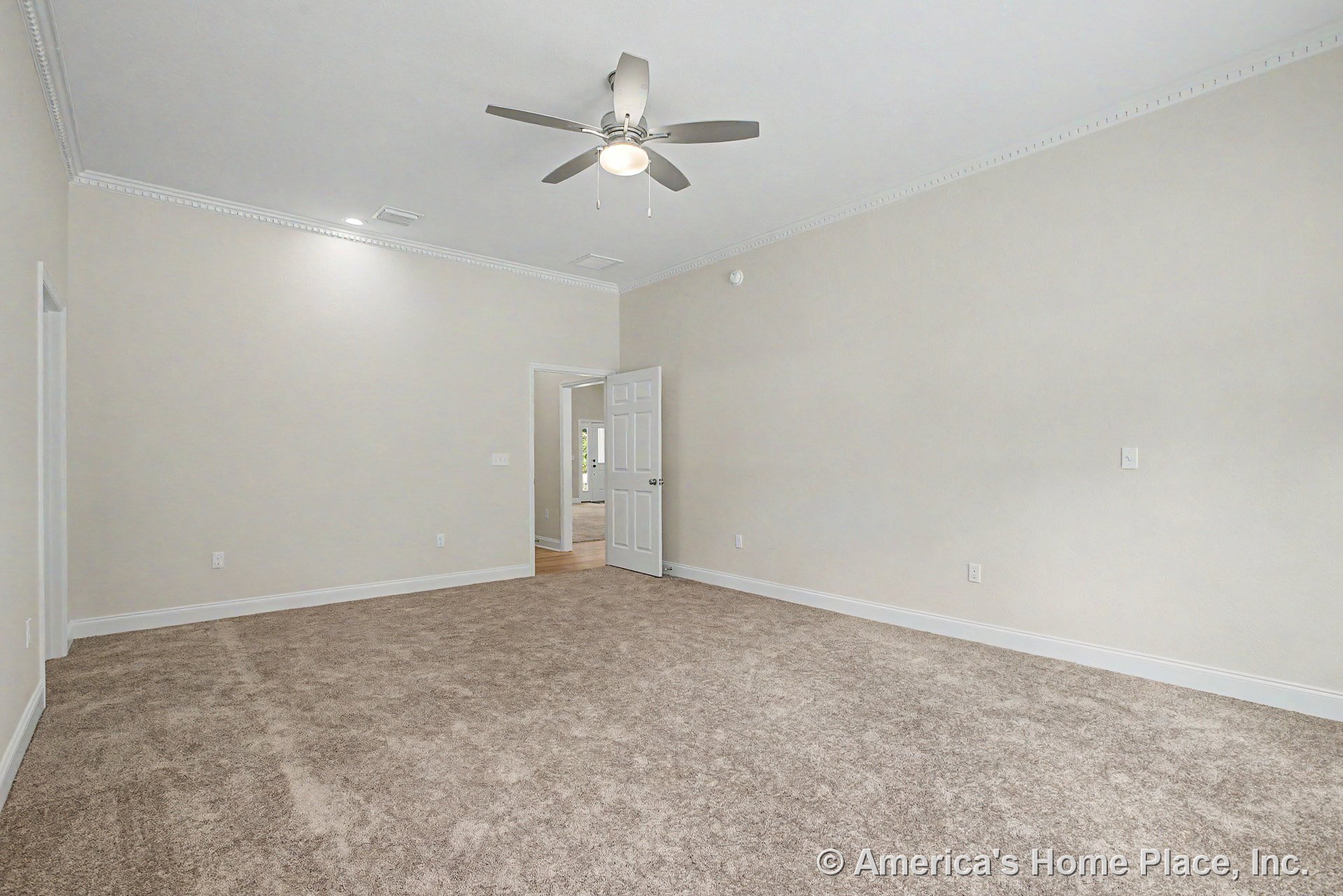 Carpeted bedroom with white crown molding, ceiling fan and light fixture, recessed ceiling light, open doorway, white trim and baseboards, and neutral walls.