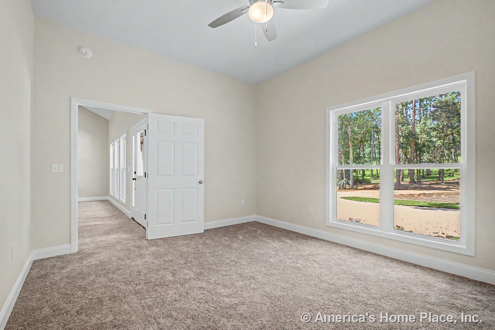 Bedroom with beige carpet flooring, large double window framed by white trim and baseboards, ceiling fan with integrated light fixture, neutral wall color, and white paneled door.