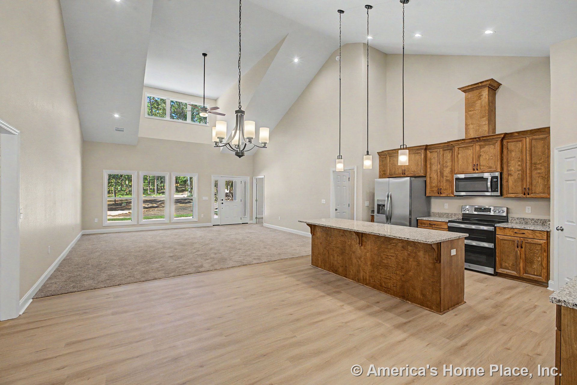 Open concept kitchen and living area with vaulted ceiling, wood cabinetry, granite countertops, stainless appliances, pendant and chandelier lighting, large window wall, carpet and