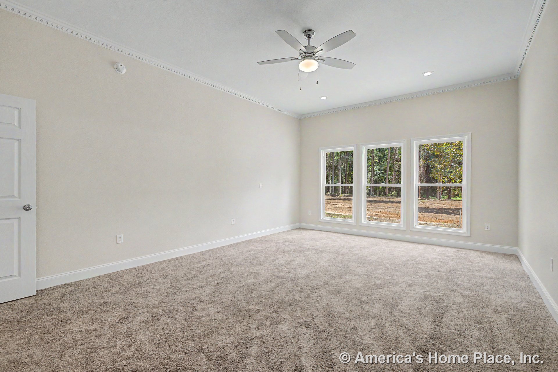 Spacious bedroom with carpet flooring, three large windows, ceiling fan with light, white crown molding, recessed ceiling lights, neutral wall color, and baseboard trim.