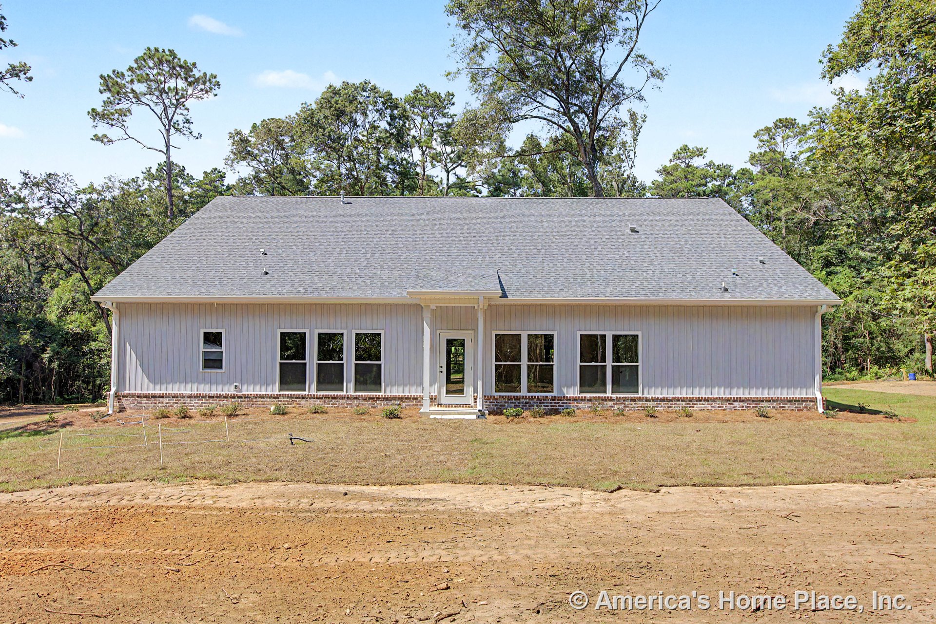 Single-story home with vertical siding, gable roof, brick foundation trim, multiple large windows, central glass door, and covered entry porch.