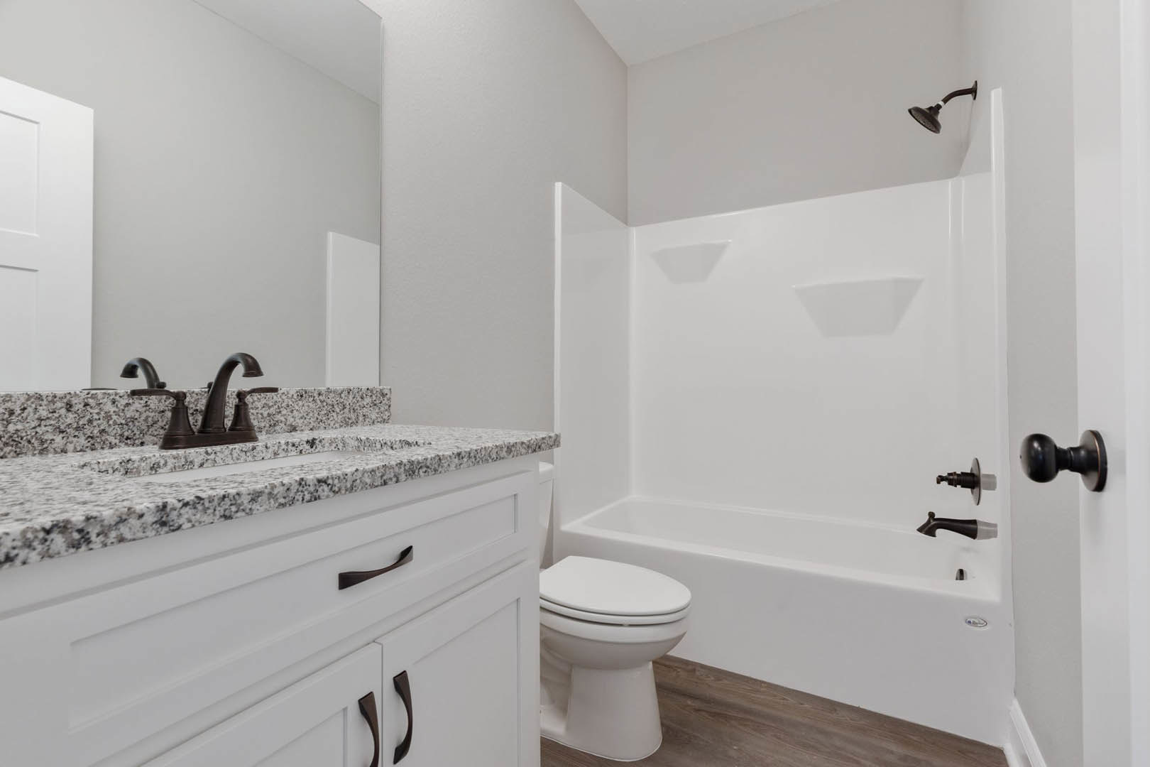 Modern bathroom with white porcelain sink, chrome faucet, white toilet, tiled walls, and stone countertop