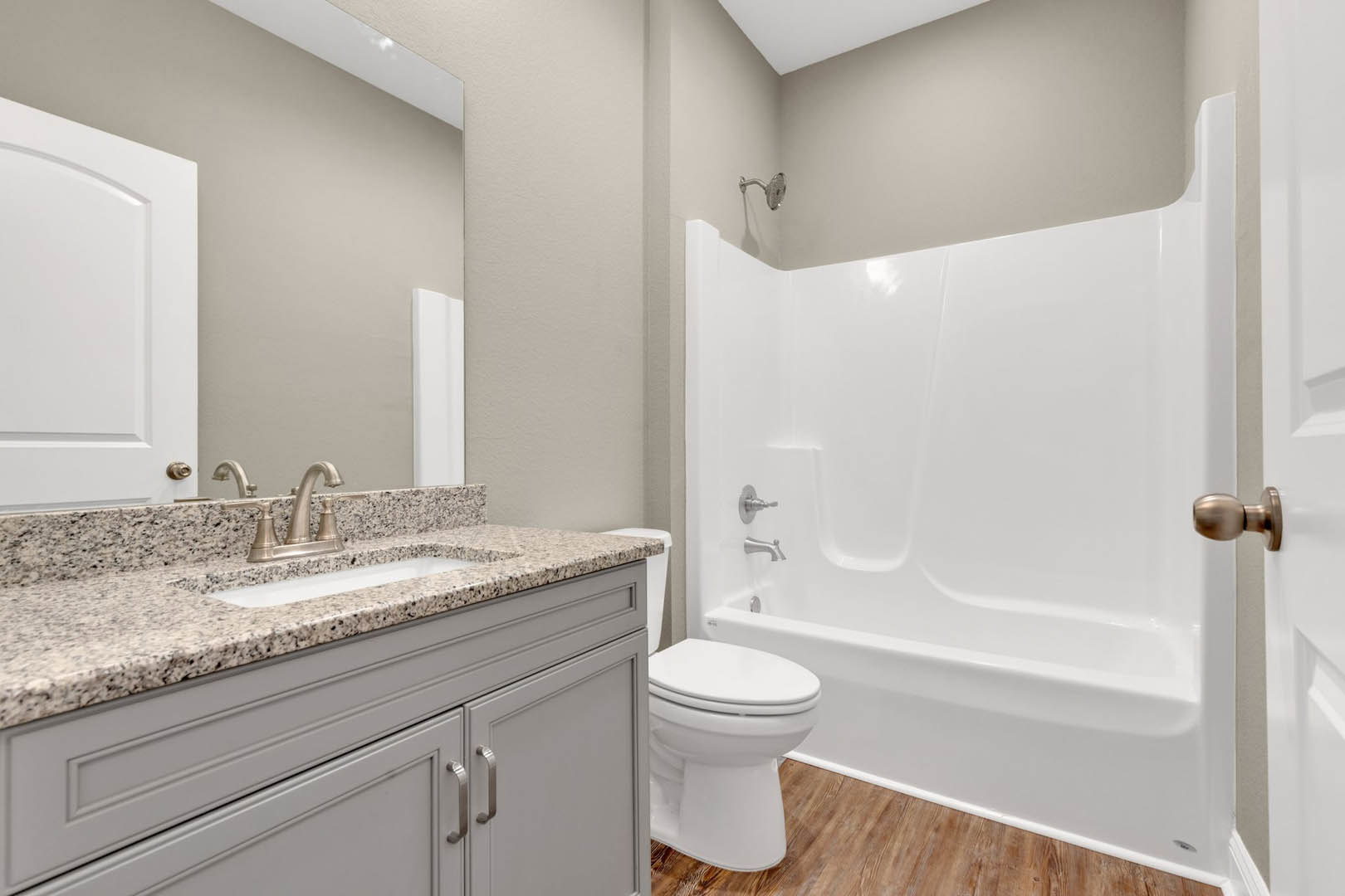 Modern bathroom featuring a white bathtub, toilet with closed lid, sleek countertop sink, chrome faucet, and white cabinetry against tiled walls