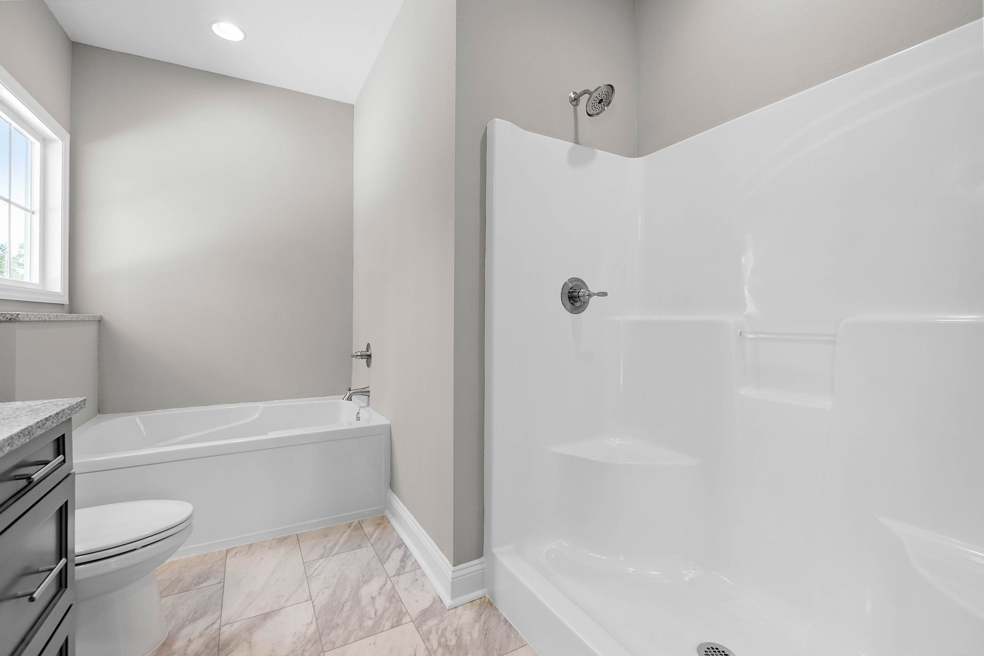 Modern bathroom featuring a freestanding bathtub, glass-enclosed shower with tile walls, black vanity cabinet, chrome fixtures, and large window providing natural light