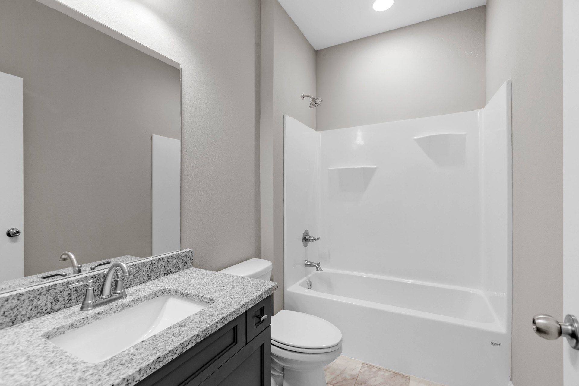 White tile bathroom with built-in tub, white toilet, and rectangular sink with chrome faucet