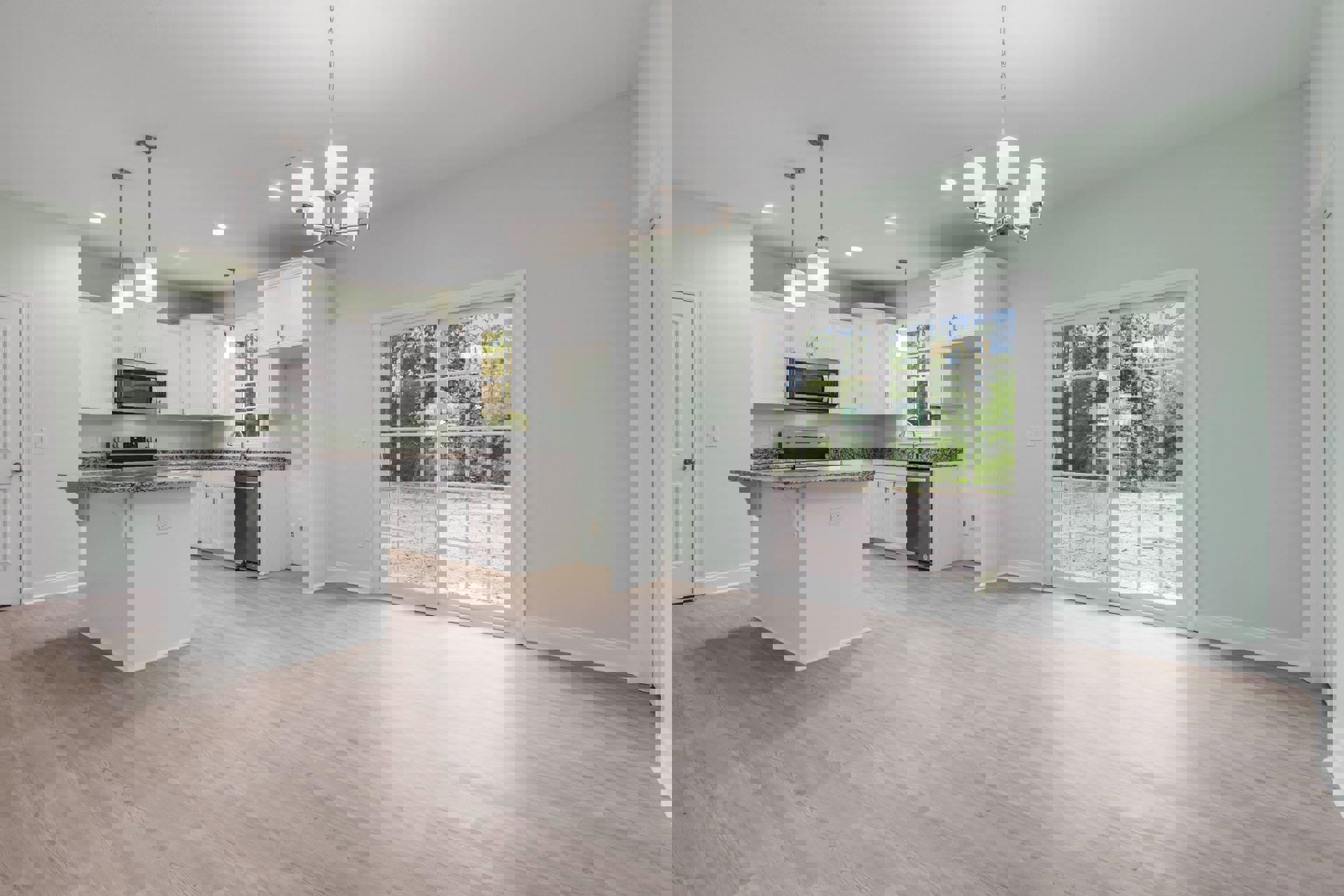 Open kitchen and dining area with wood flooring, white kitchen island topped with granite, cabinetry, stainless steel sink, microwave with glass window, sliding glass door leading