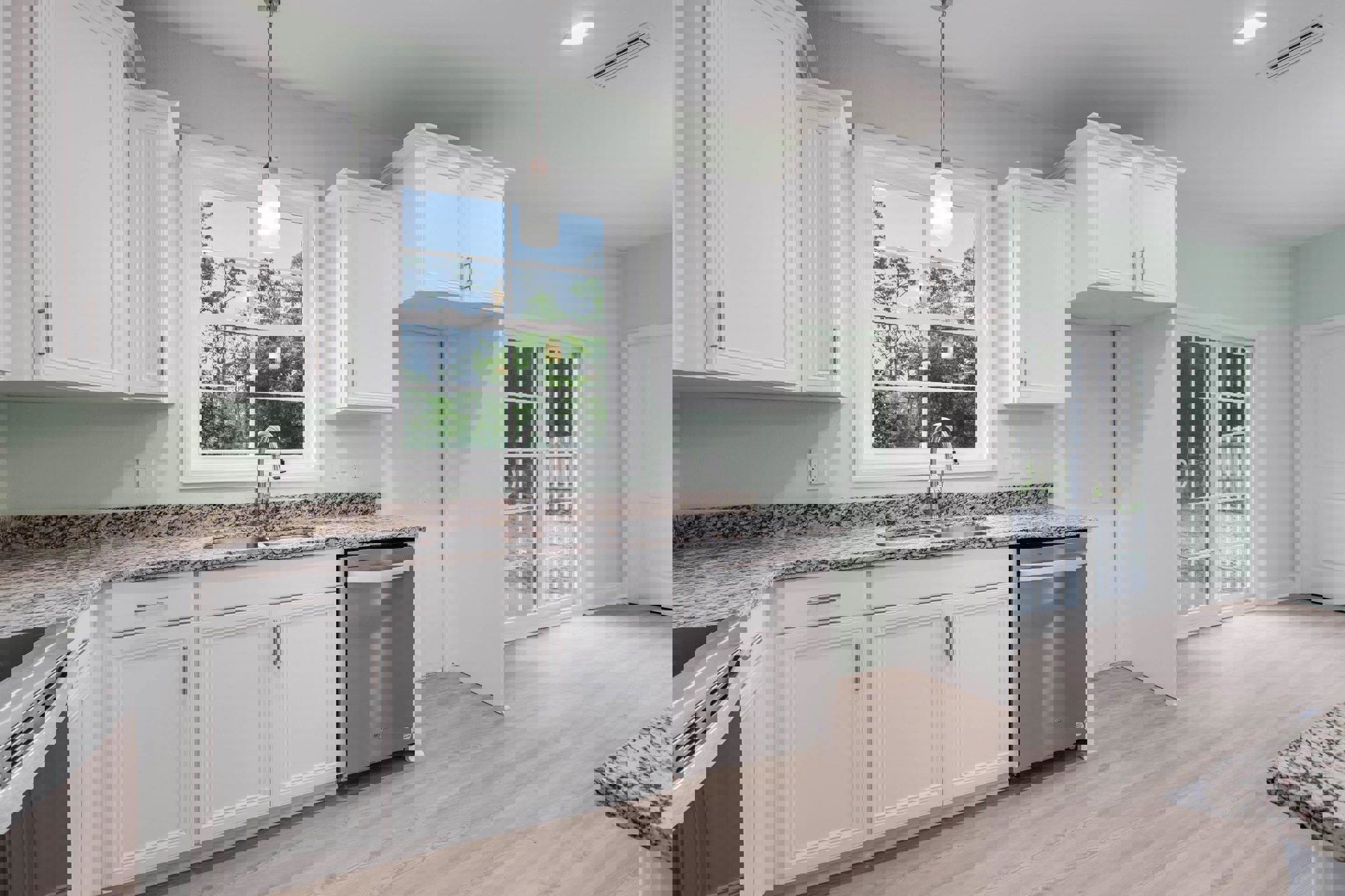 White kitchen cabinets with granite countertops, stainless steel refrigerator, window with natural light, white pendant light fixture, island with metal support pole, close-up of