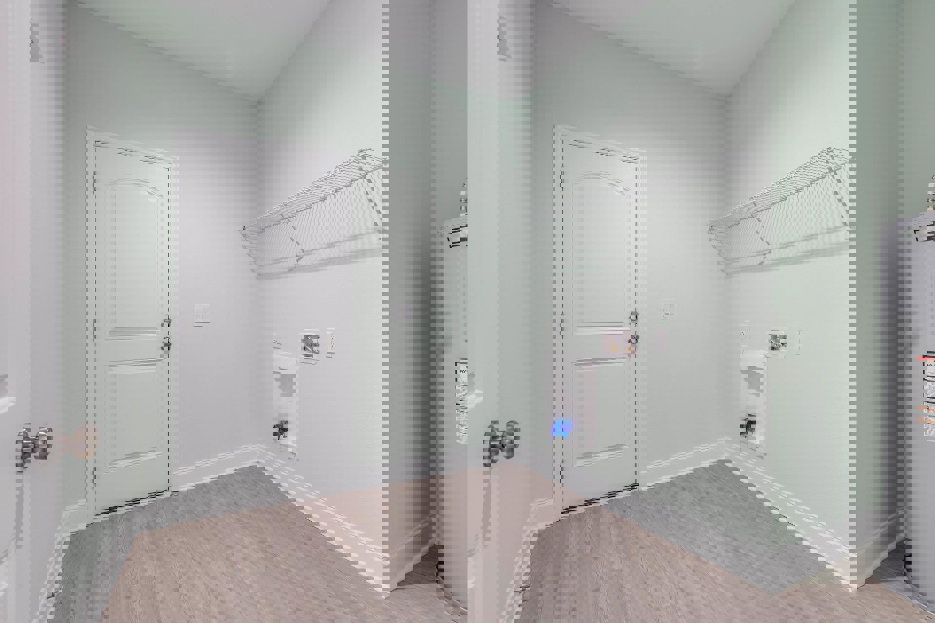 White door with silver knobs set in a white wall, wood flooring with white baseboards, built-in shelf holding a blue bag, and a poster displayed above the shelf.