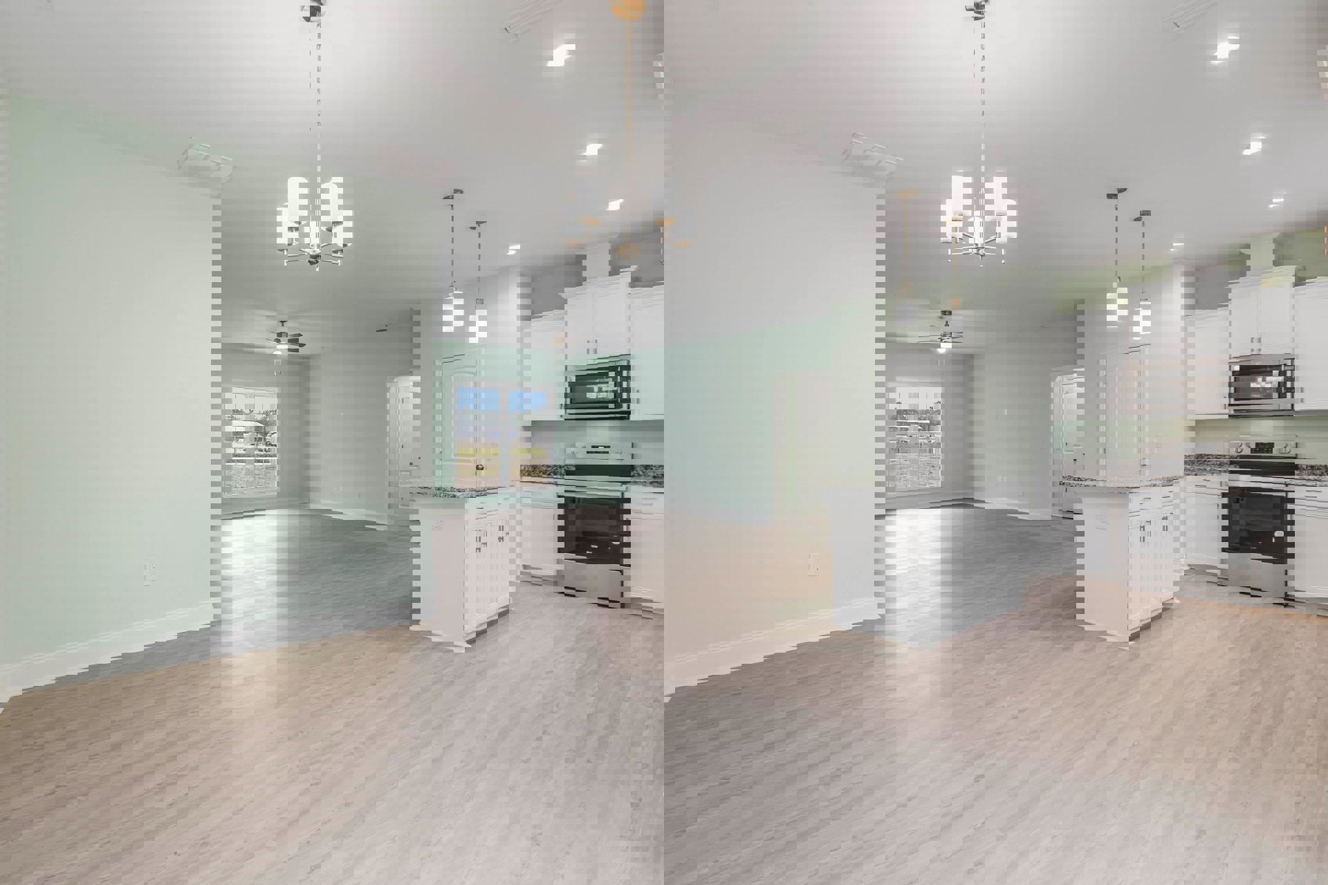 Kitchen with light wood laminate flooring, white quartz countertop, stainless steel stove, built-in microwave, white cabinetry, open white door, and window overlooking outdoor