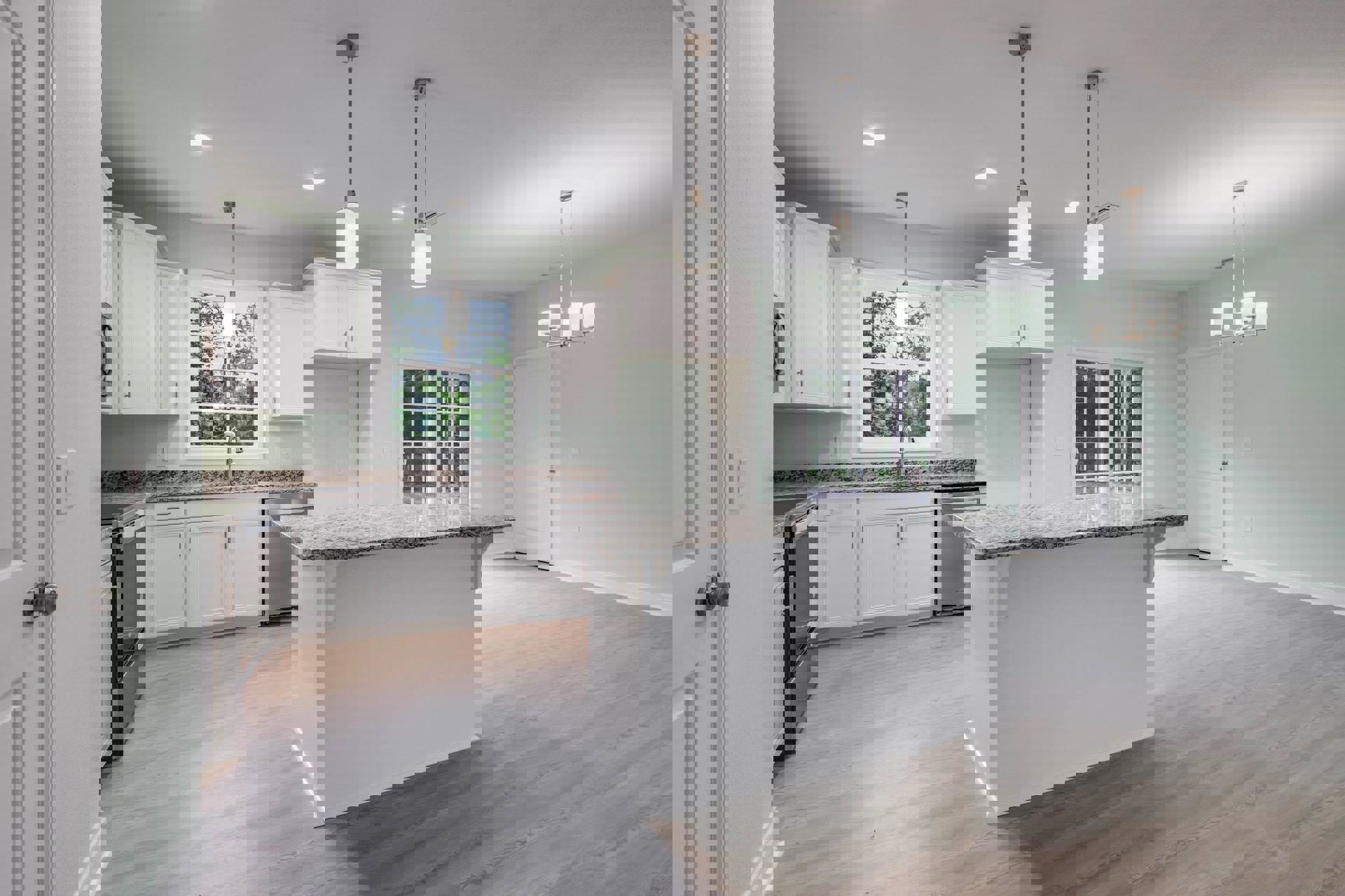 White kitchen with granite countertops, white cabinetry, stainless steel sink beneath a window, silver hardware, tile flooring, and a view of trees through the window.
