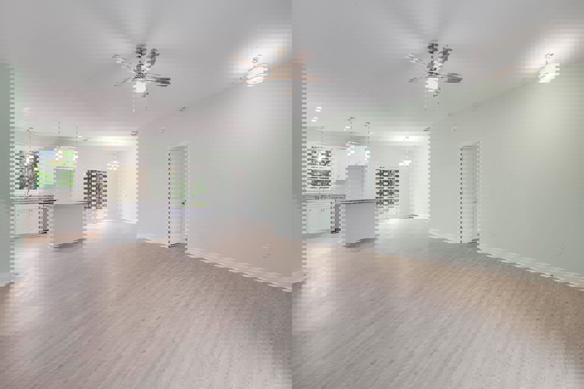 Open-concept room with wood flooring, white walls, ceiling fan with light, kitchen area featuring white cabinetry, stainless hardware, and a white door with glass panes.