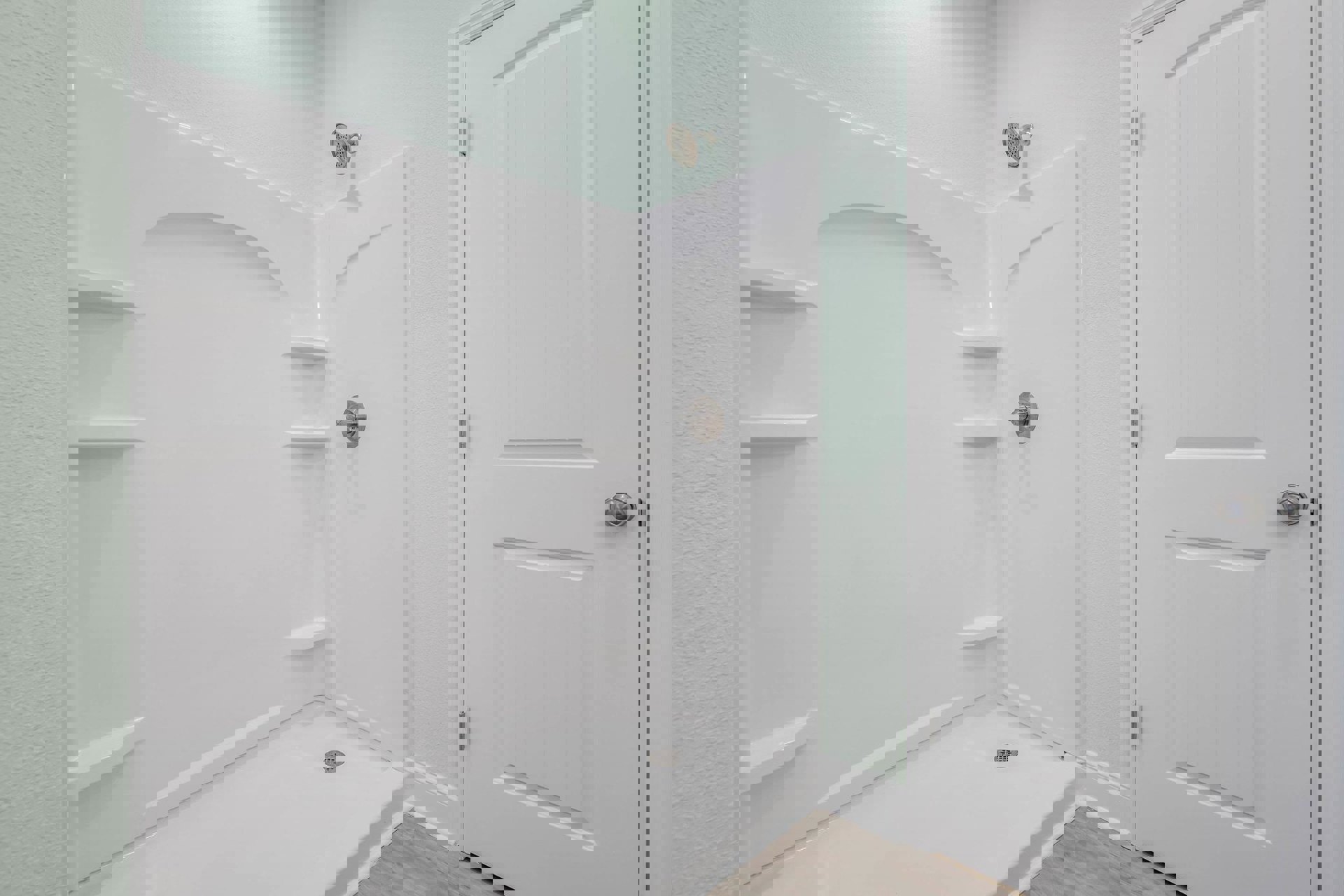 White tile shower with chrome showerhead and silver door handle in modern bathroom.