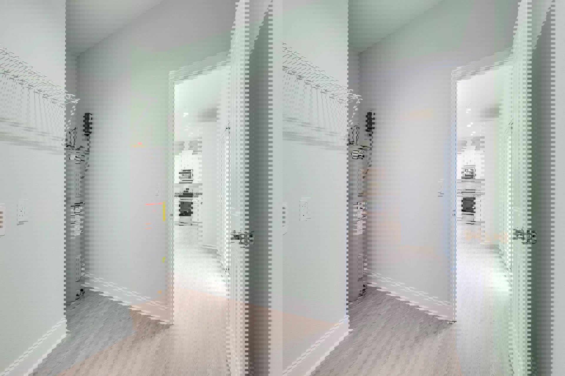 Open door revealing a utility room with grey water heater, white walls, electrical outlets, and light-colored flooring