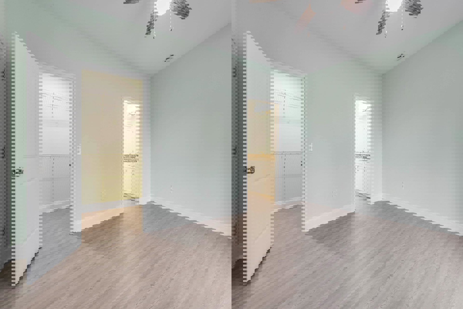 Bedroom with wood flooring, white trim, ceiling fan, white closet door, and adjacent bathroom featuring marble countertop