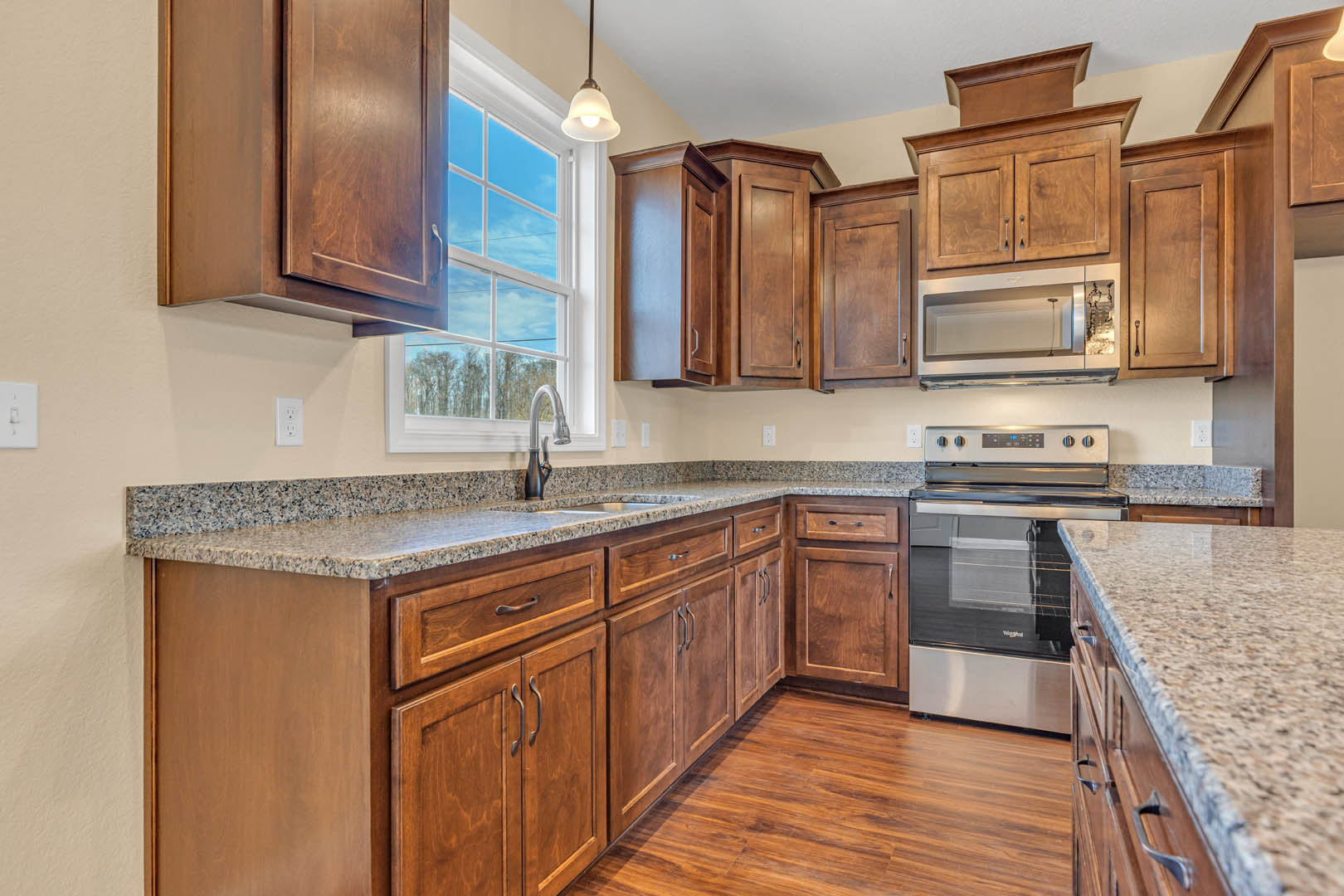 Kitchen with wooden cabinets, granite countertops, stainless steel oven with glass door, open refrigerator, close-up of window and faucet, ceiling light fixture