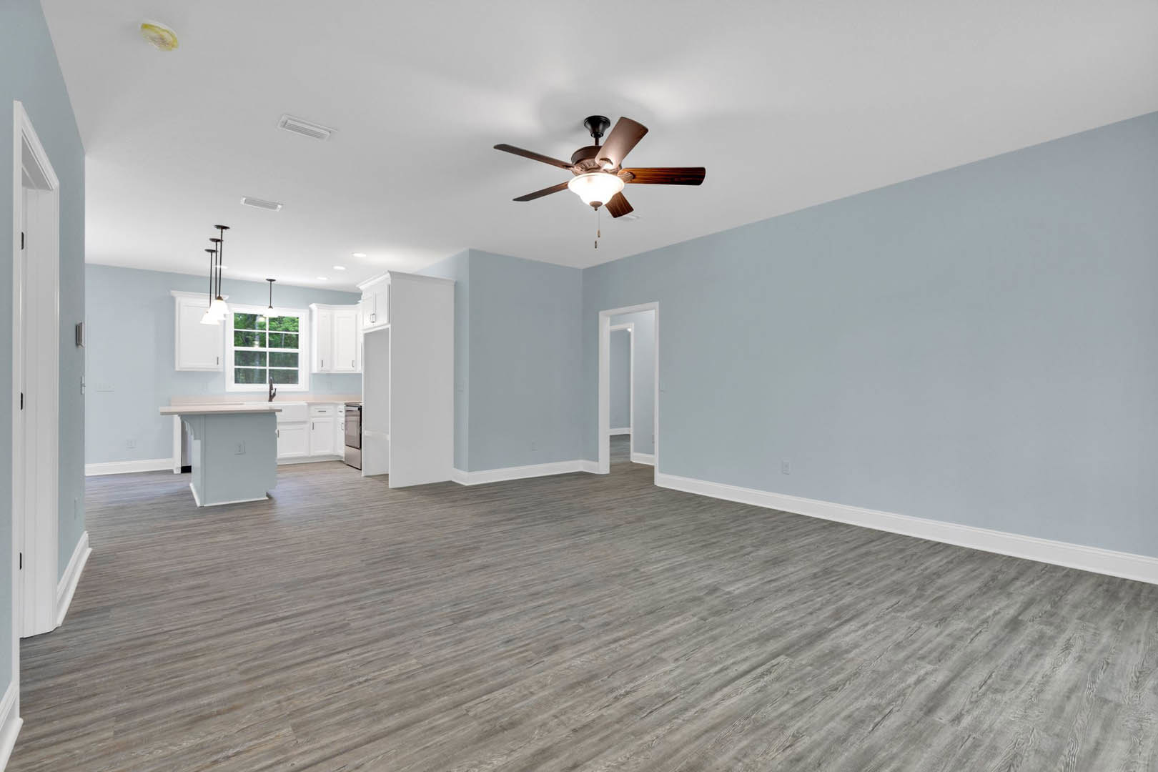 Ceiling fan with light fixture above wood laminate flooring, white walls with framed trim, white table, yellow and white decor object