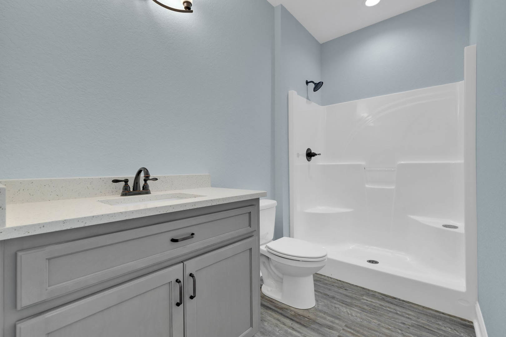 Modern bathroom featuring a white tile shower, sleek countertop with chrome faucet, white toilet, and light wood cabinetry.