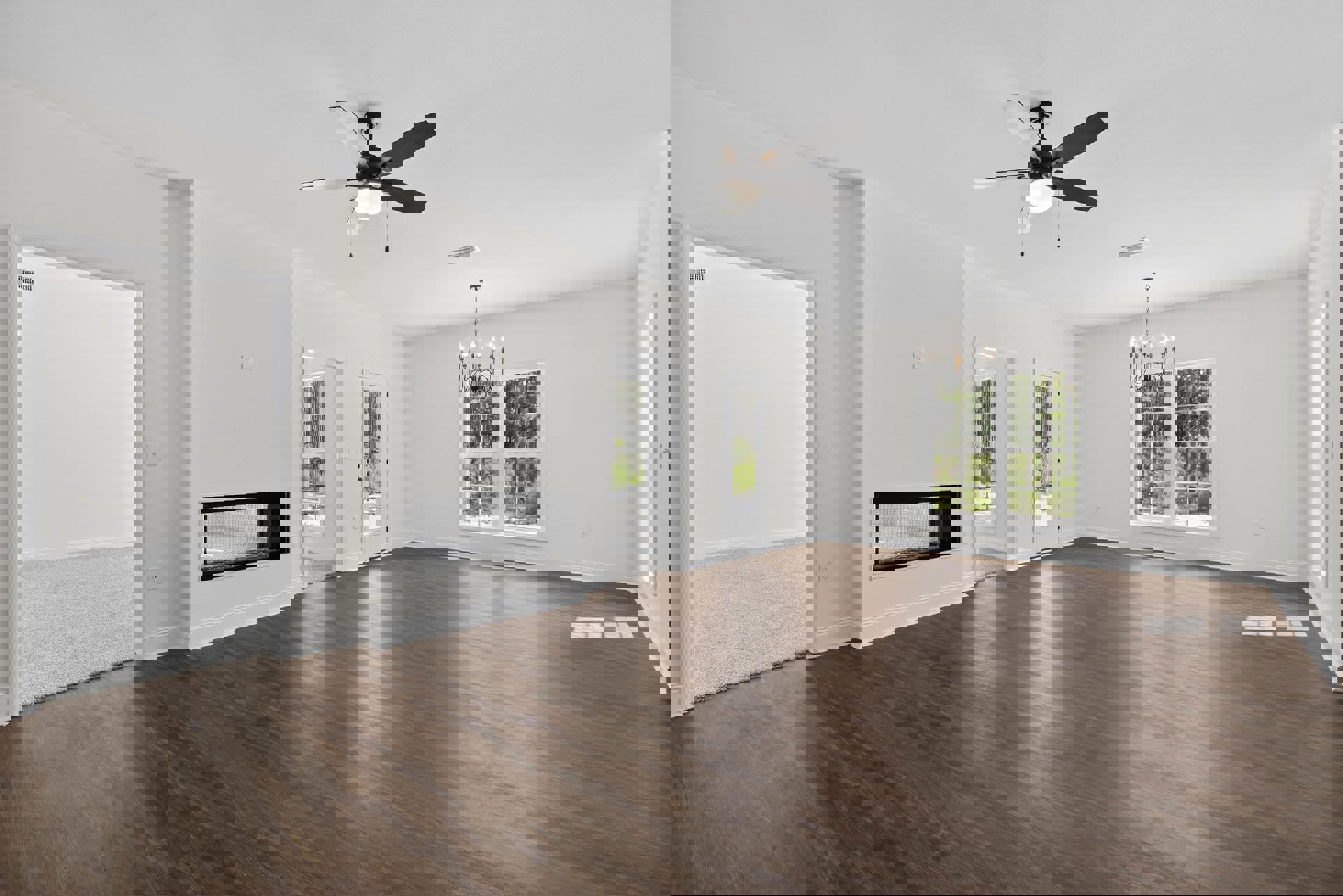 Spacious living area with wood flooring, ceiling fan with light, fireplace, white door with glass window, and large windows letting in natural light