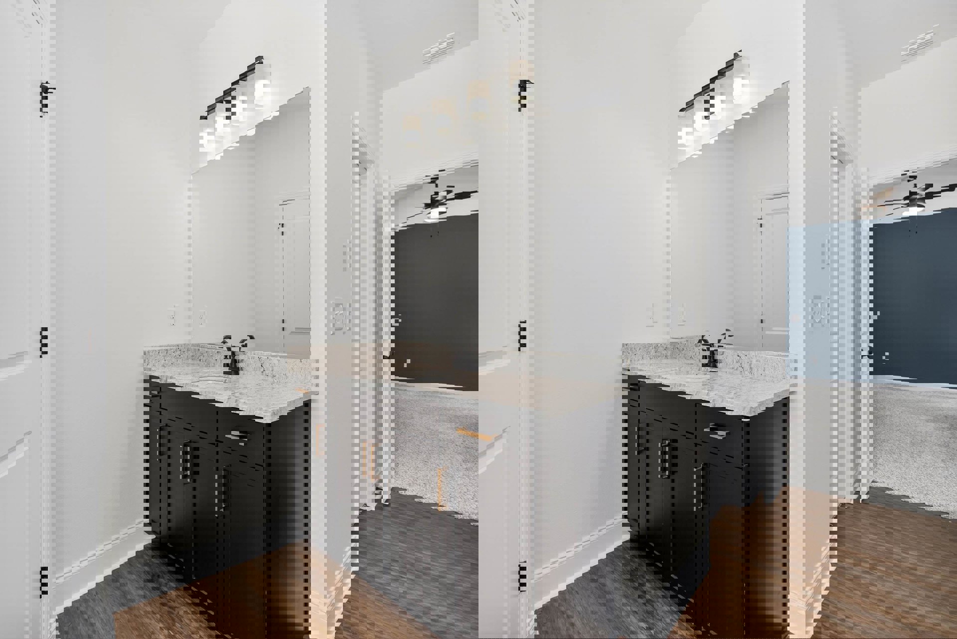 Bathroom with white marble countertop and black cabinetry, rectangular mirror above sink, white walls, black door handle, wall-mounted light fixture