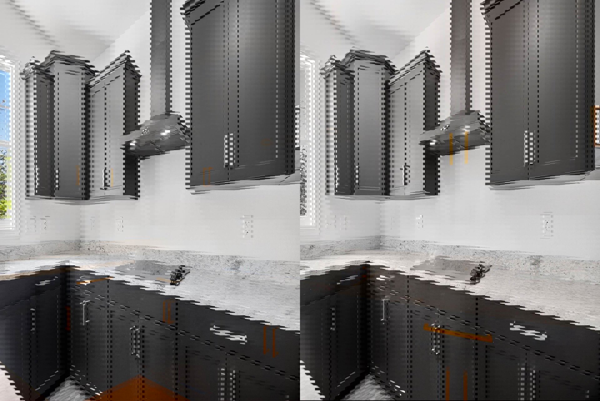 Black kitchen cabinets with marble countertops, stainless steel stove, tile backsplash, undermount sink, and large window showing clear blue sky