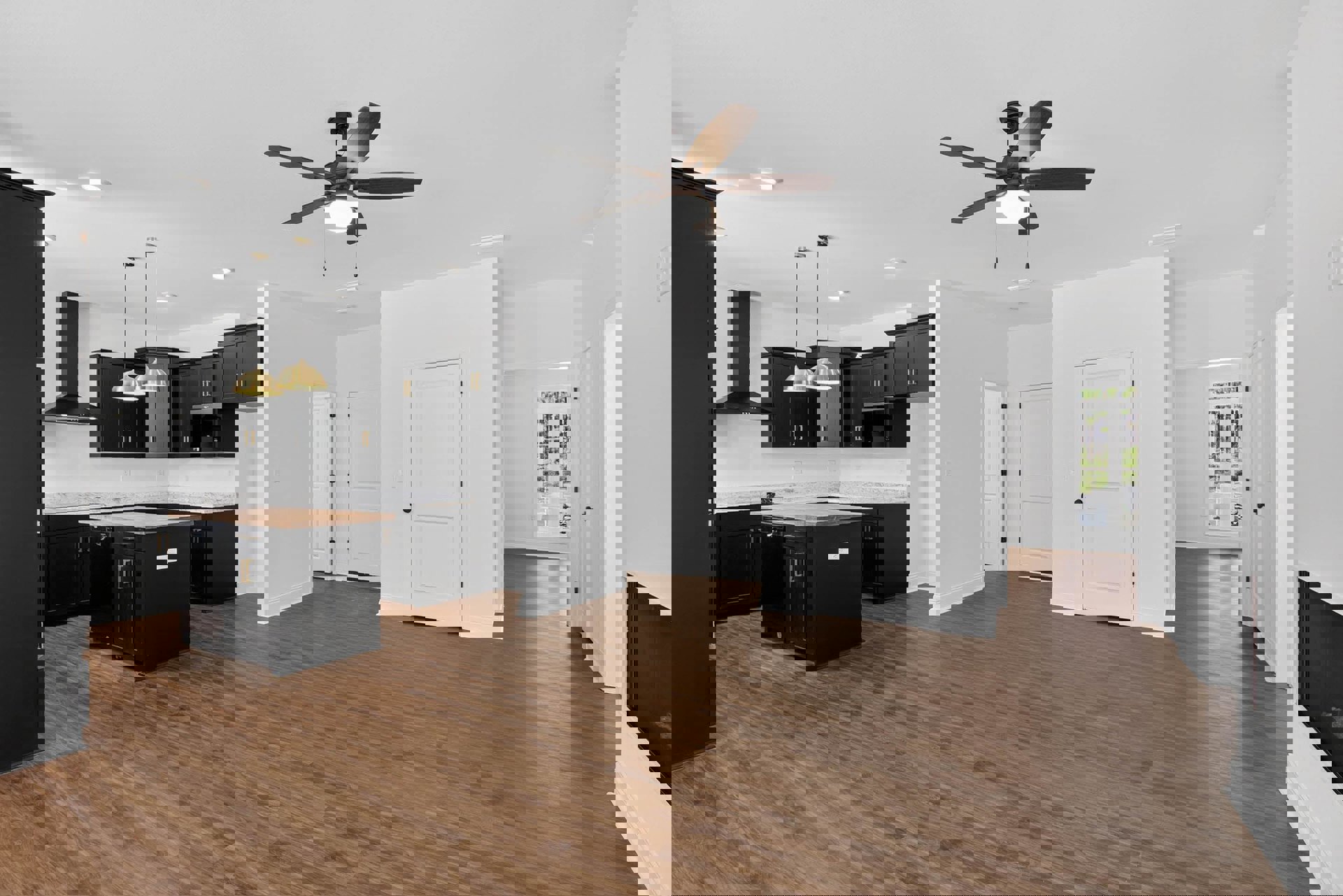 Open kitchen with black cabinetry, wood countertops, and stainless appliances; ceiling fan with light fixture above wood flooring; white door with black hardware visible in