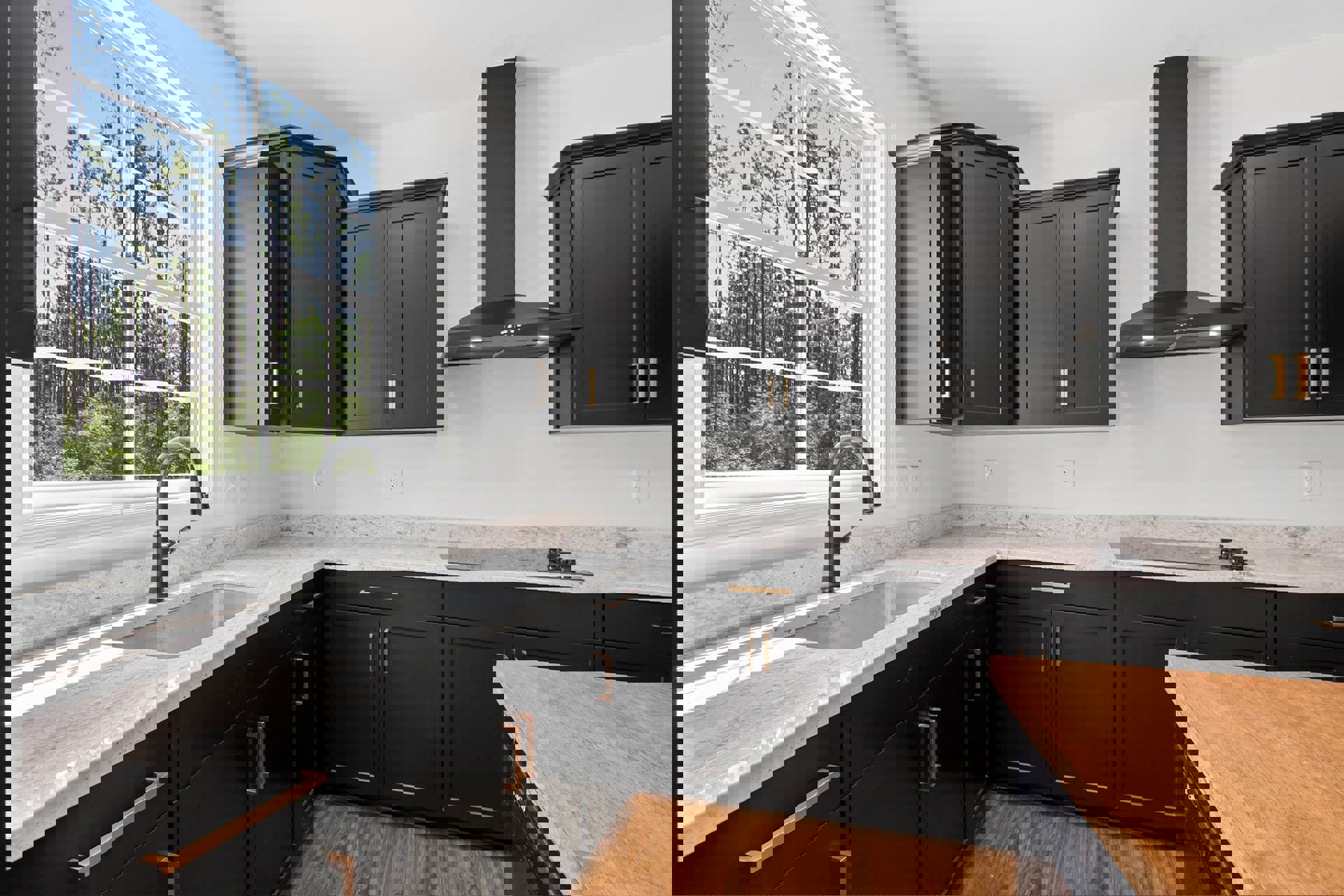 Black kitchen cabinets with gold handles, marble countertops, wood island, stainless steel faucet, window overlooking trees, under-cabinet lighting