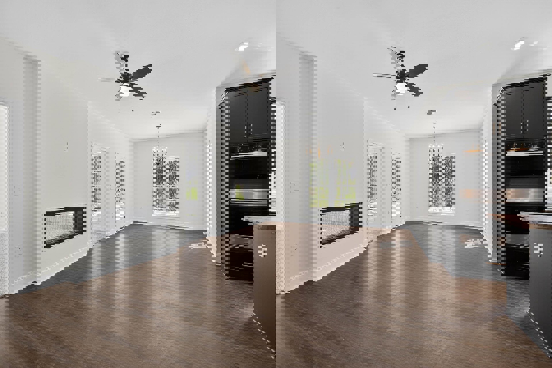 Spacious room with white walls, wood laminate flooring, ceiling fan with light, large window with mesh screen, black and silver oven, and built-in cabinetry