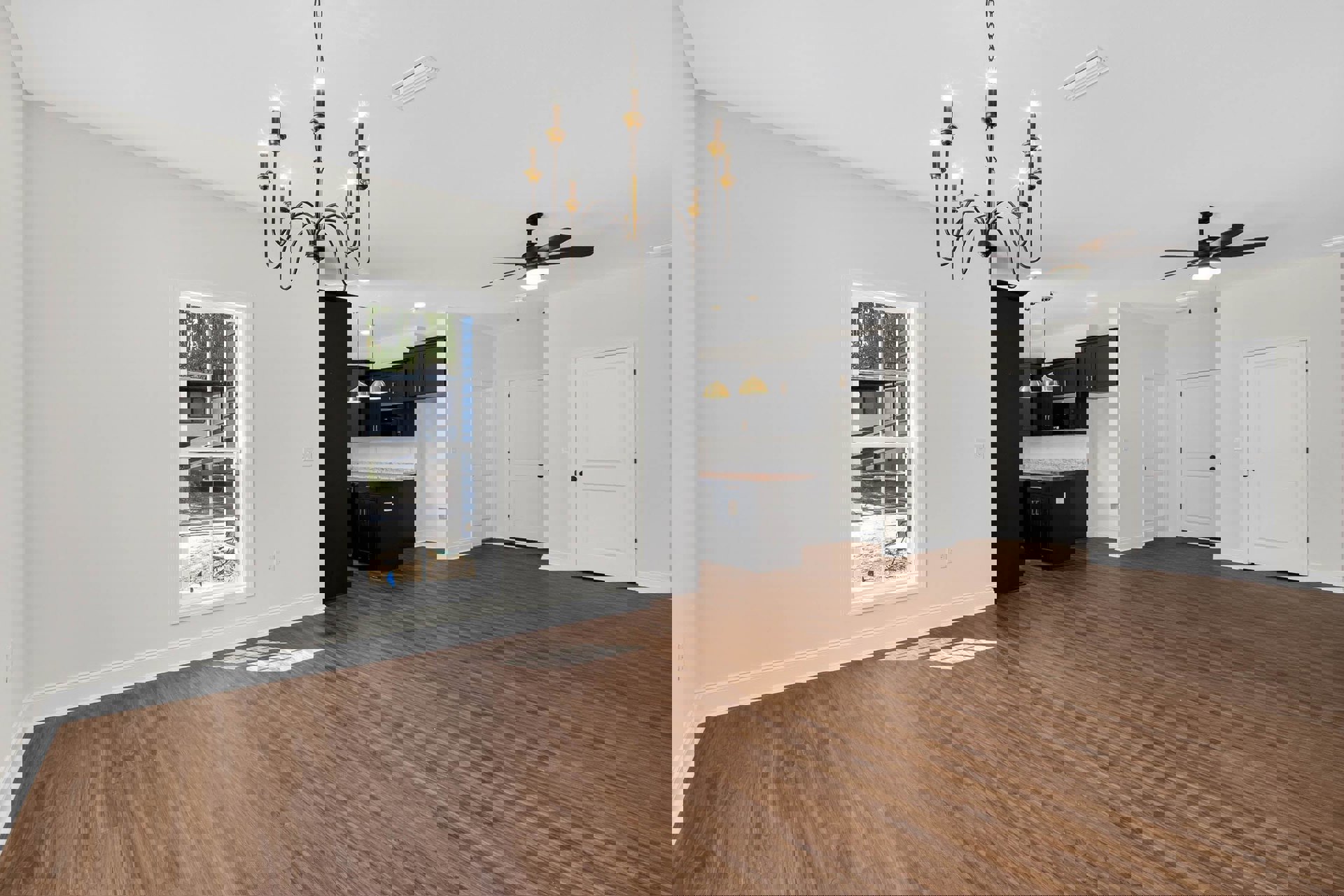 Hardwood floor room with black cabinet, white walls, white doors with black hardware, chandelier lighting, window overlooking boat