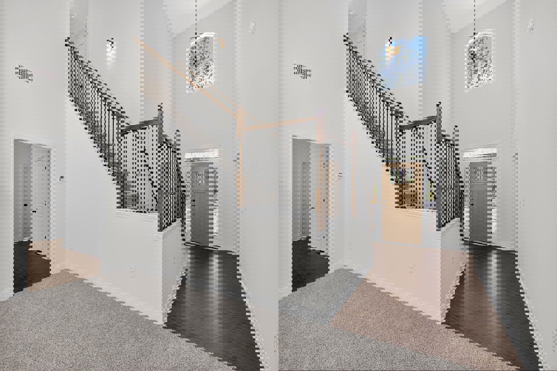 Hardwood staircase with black metal railing, brown door with glass panels, hallway featuring light fixture, wall vent, and plaster walls.