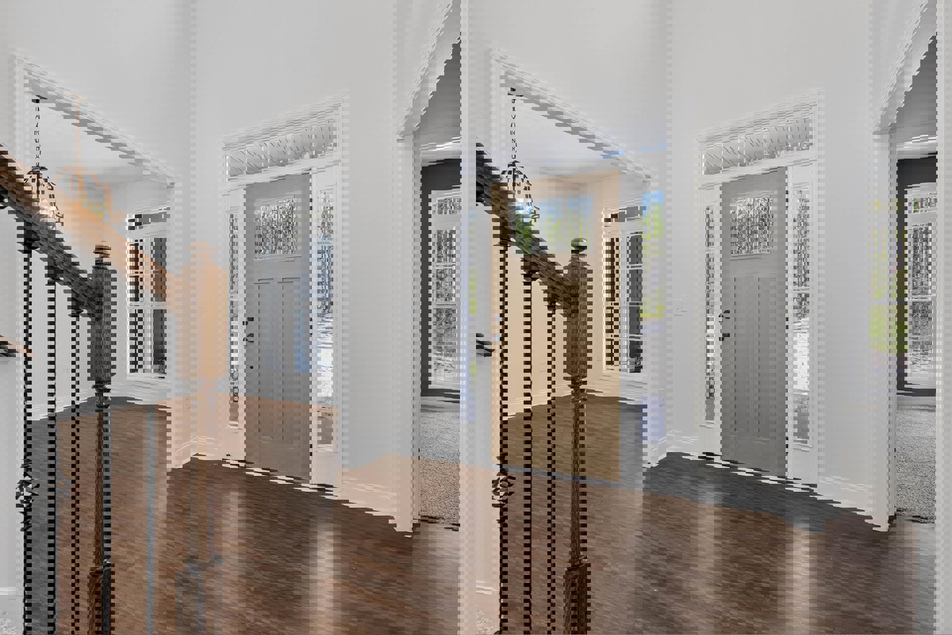 White walls, hardwood floor, brown door with glass panes, wooden railing, window with molding