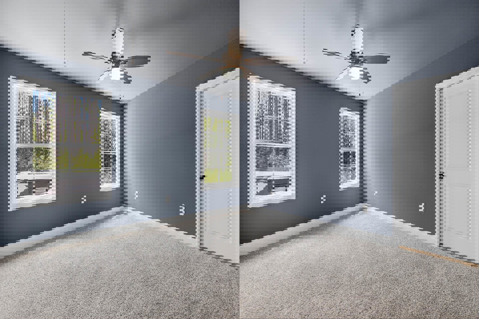 Carpeted room with a ceiling fan and light, two windows showing leafy trees, white door with black handle, white walls and crown molding