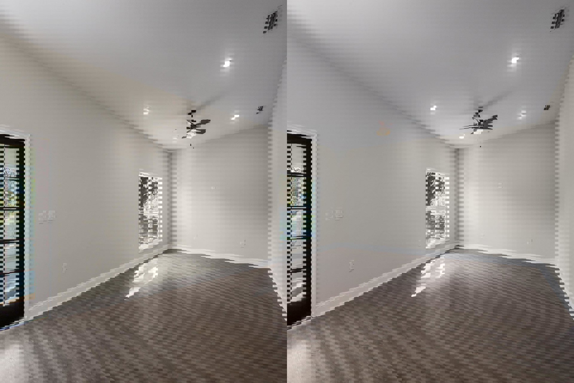 Wood flooring and white walls in a bright room with a ceiling fan, window overlooking trees, and a close-up view of a door