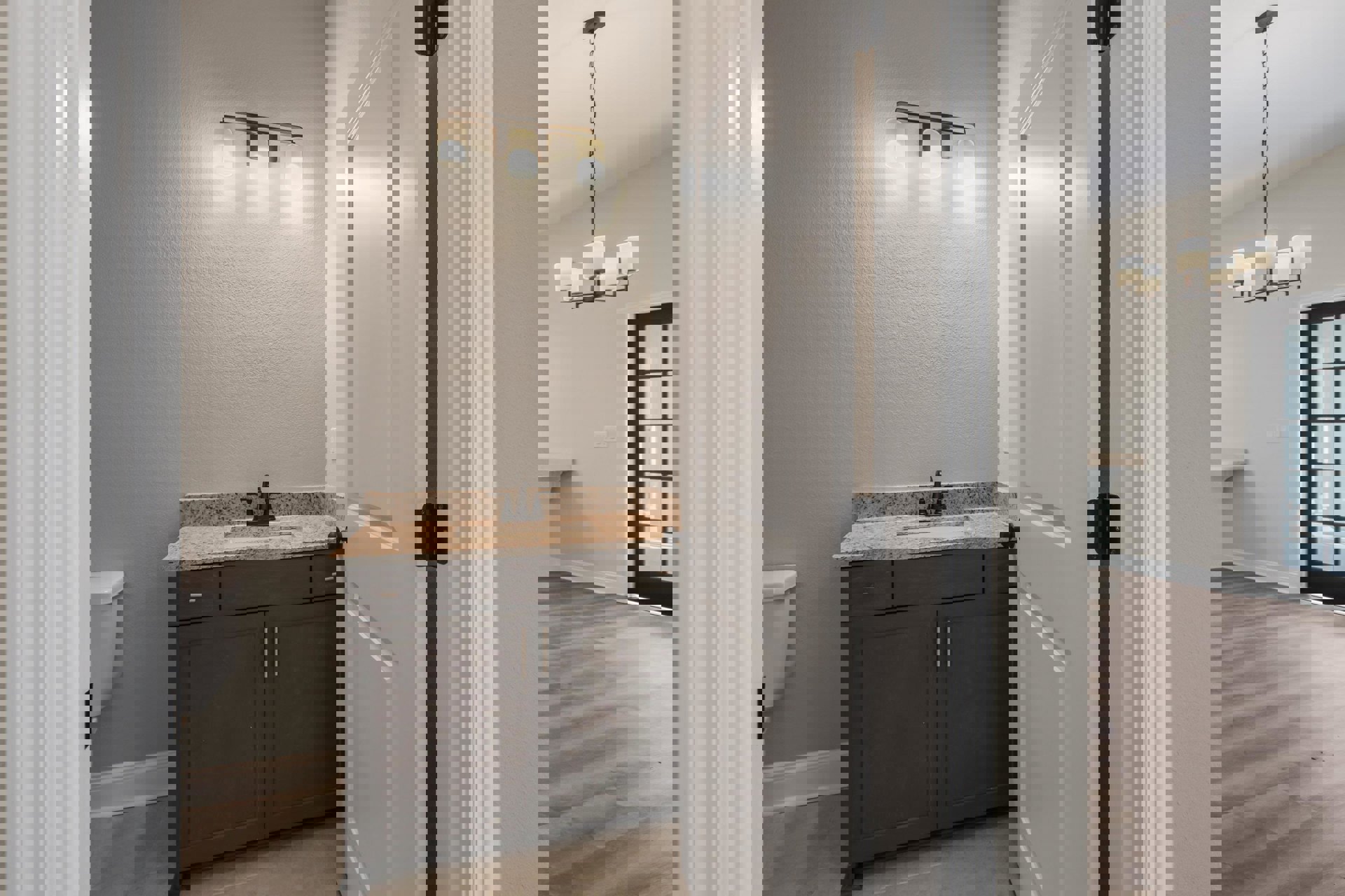 Modern bathroom with white ceramic sink, wall-mounted faucet, rectangular mirror, and toilet; light fixture above sink, neutral tile walls and floor, window providing natural light