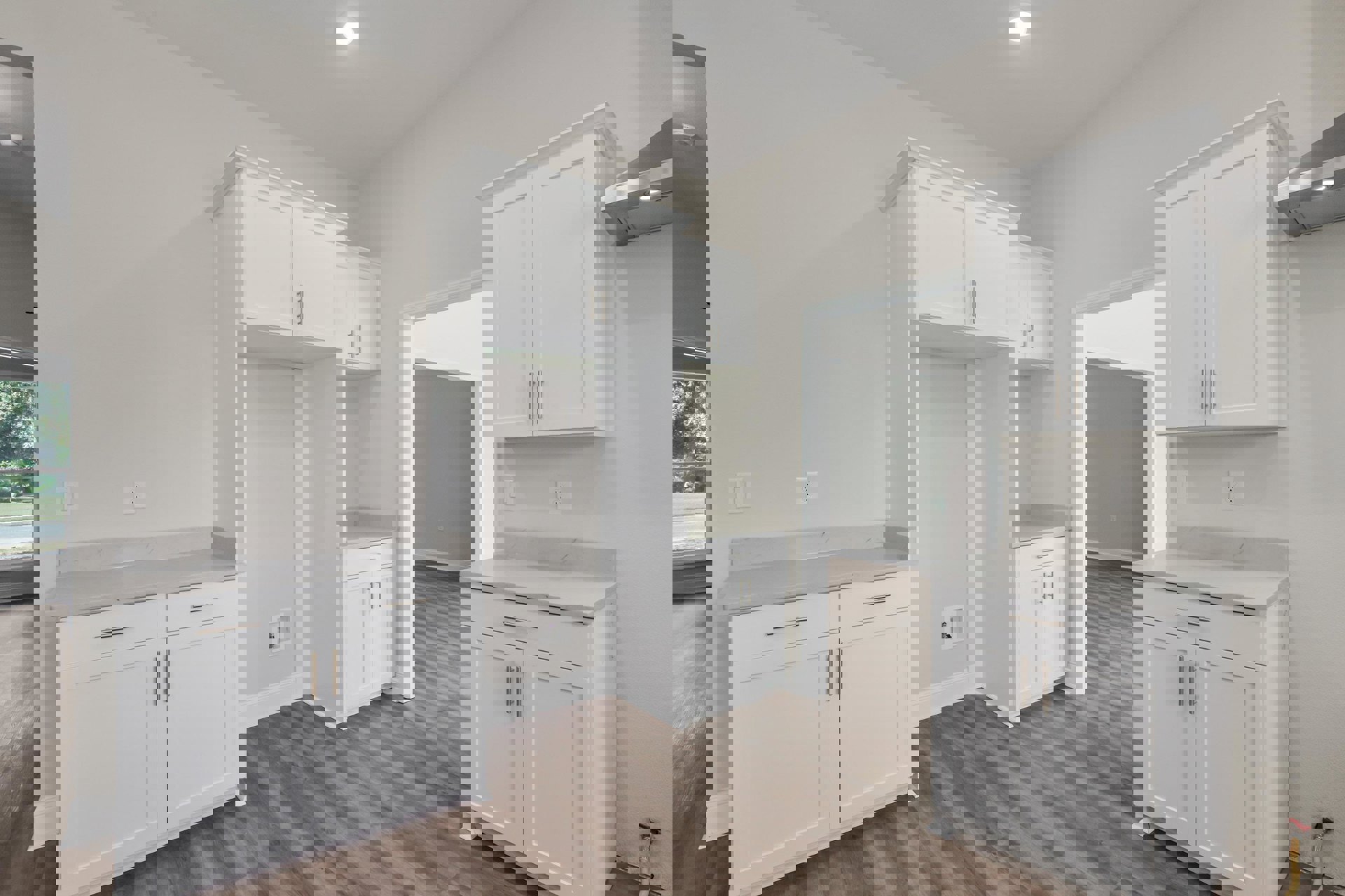 White kitchen cabinets with silver handles, marble countertop, hardwood flooring, and stainless steel sink.