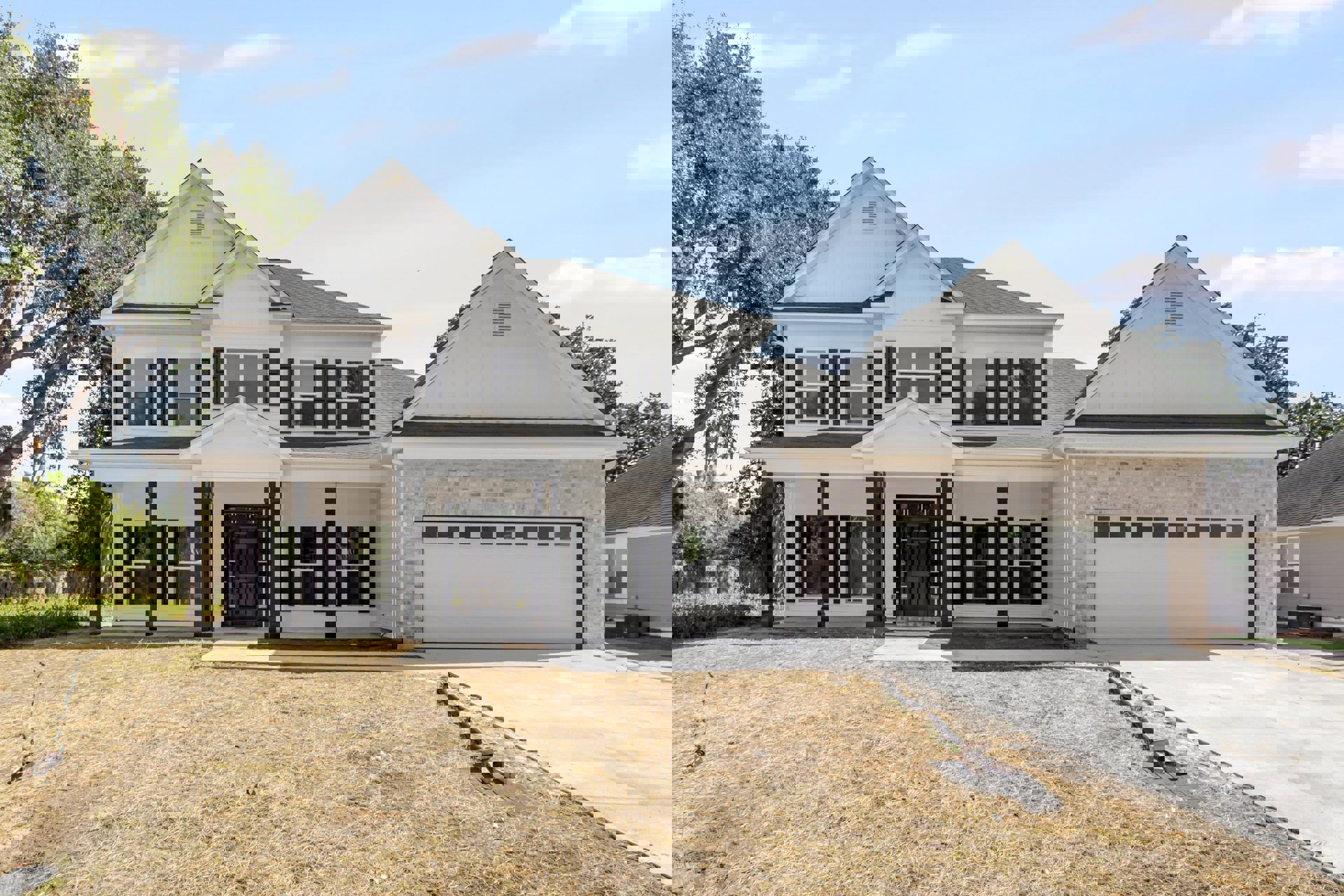Two-story home with white siding, black front door with glass panes, white-framed windows, attached garage, manicured green lawn, and mature tree in front yard.
