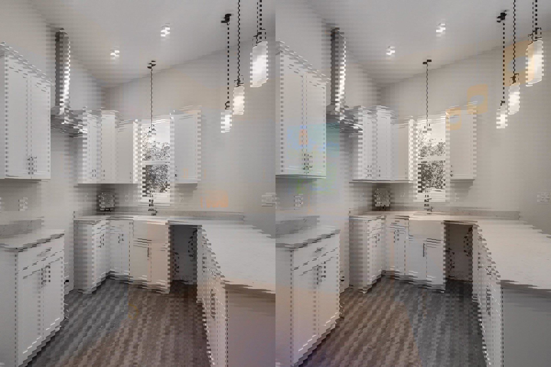 White kitchen with marble countertops, silver cabinet handles, wood flooring, and a white pendant light fixture