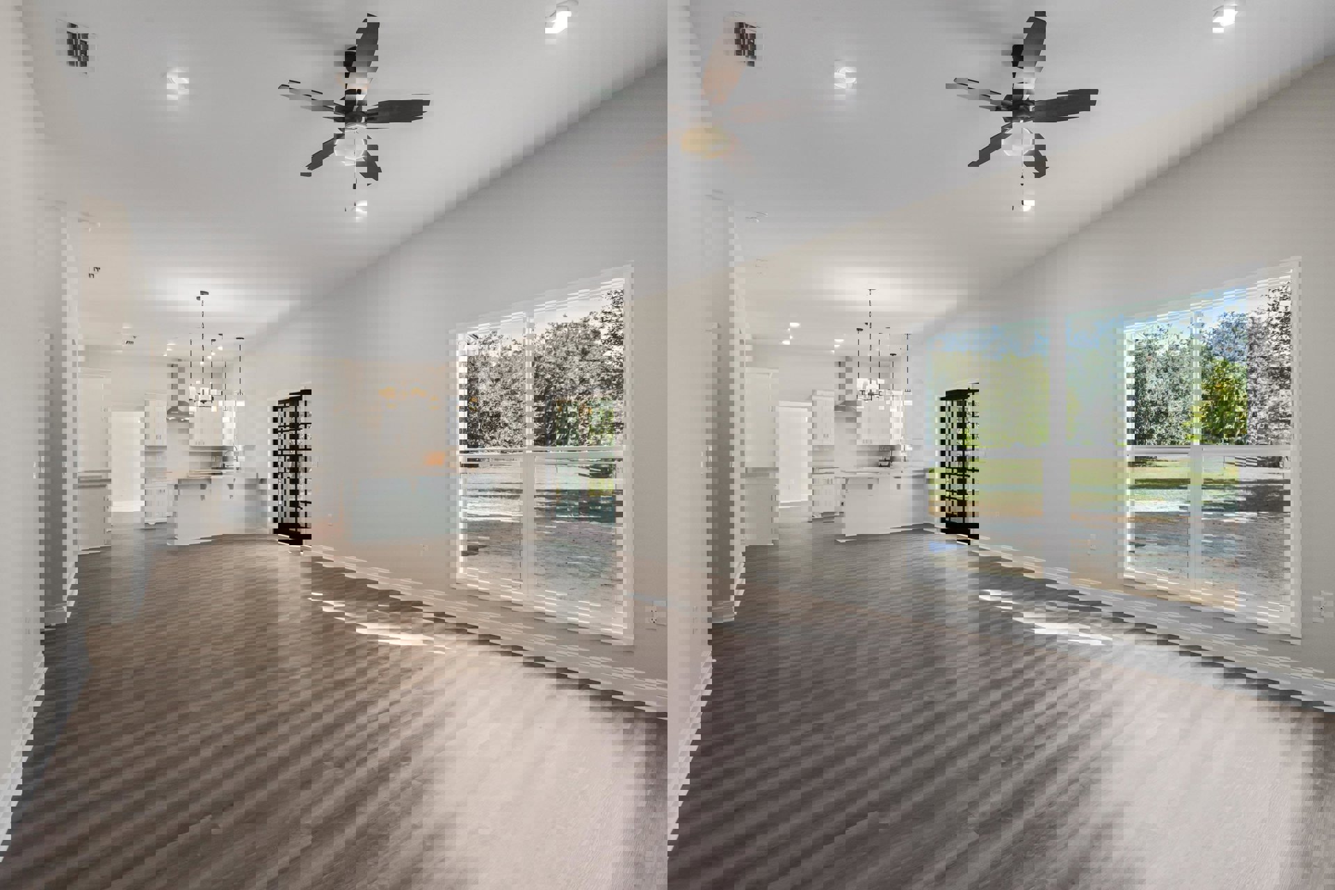 Spacious room with wood flooring, ceiling fan with light, white walls, large window showing trees outside, and a closed door