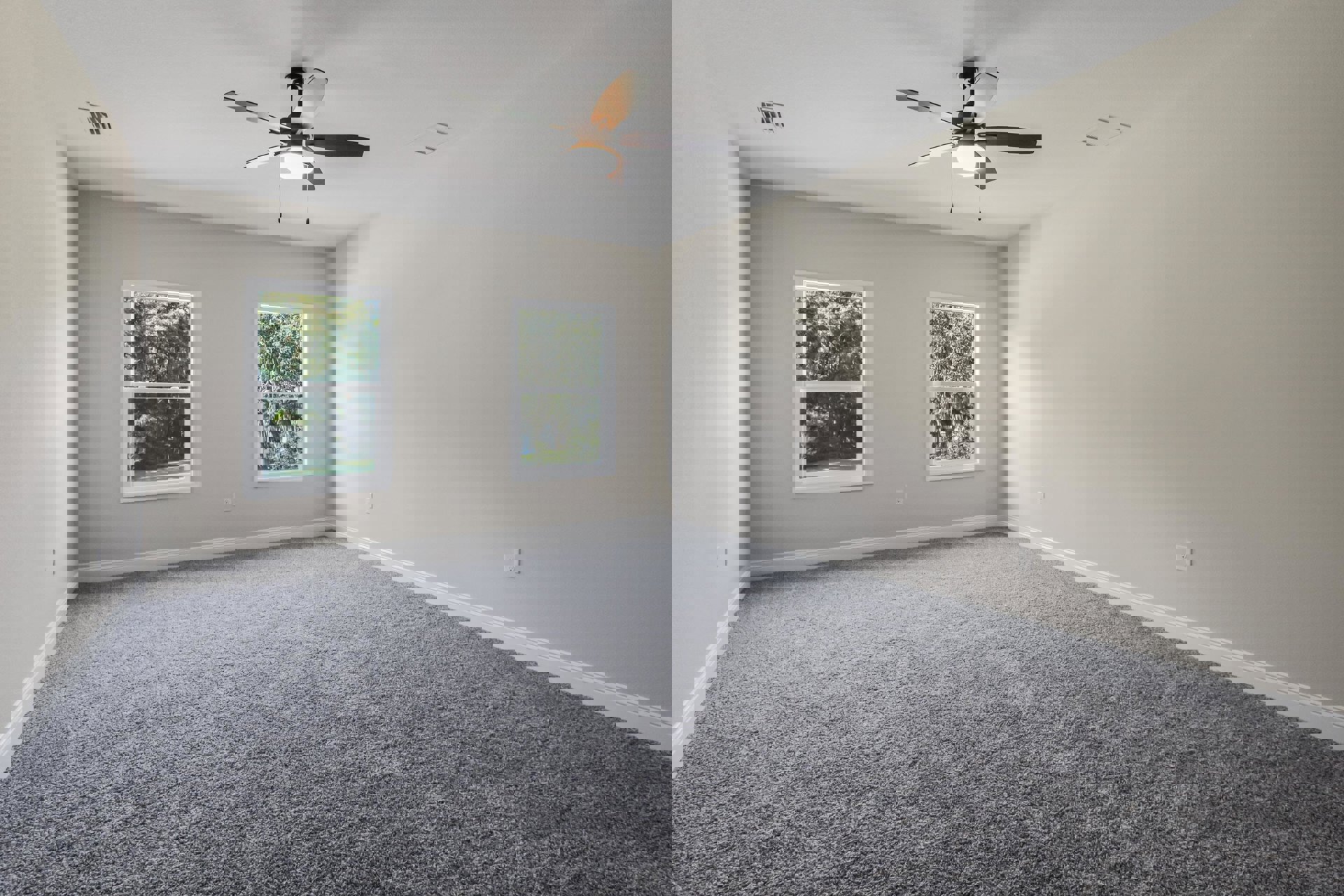 Bedroom with grey carpet, white walls, ceiling fan with light, and large windows overlooking trees.