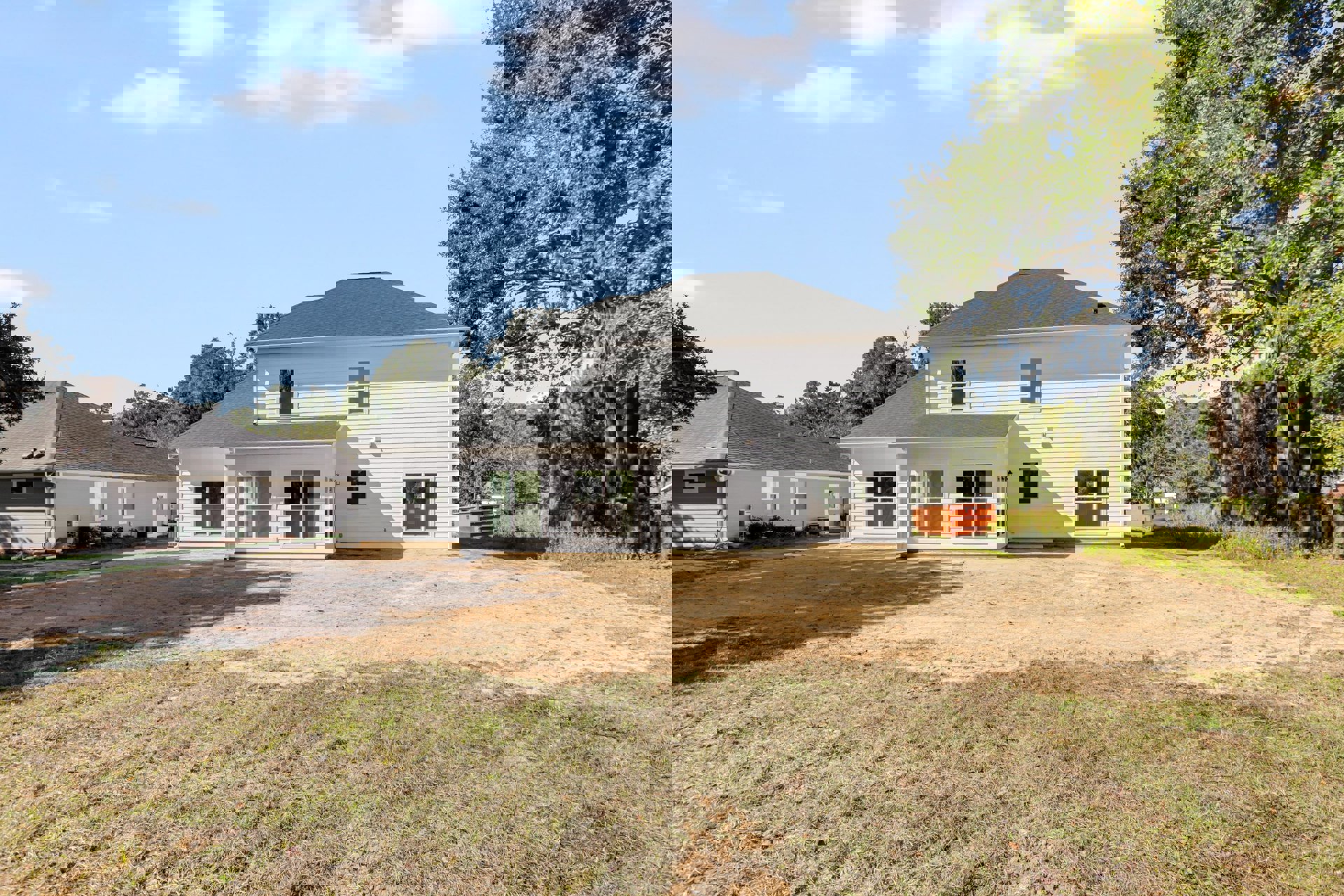 White house with black roof, large front tree, dirt backyard, orange dumpster with logo, close-up window, cloudy sky