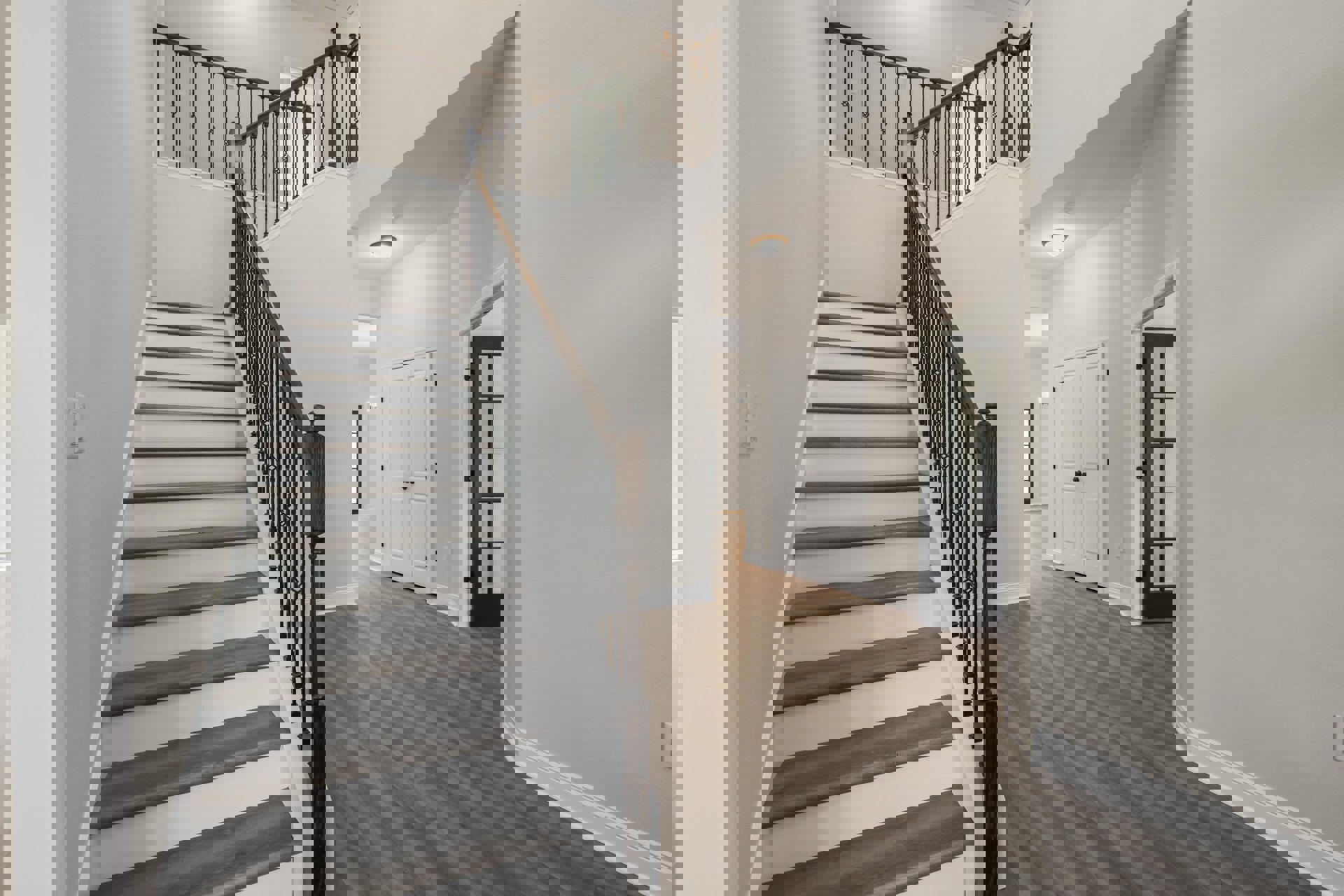 Wood staircase with black metal railing beside white double doors with black hardware, light plaster walls, and hardwood flooring