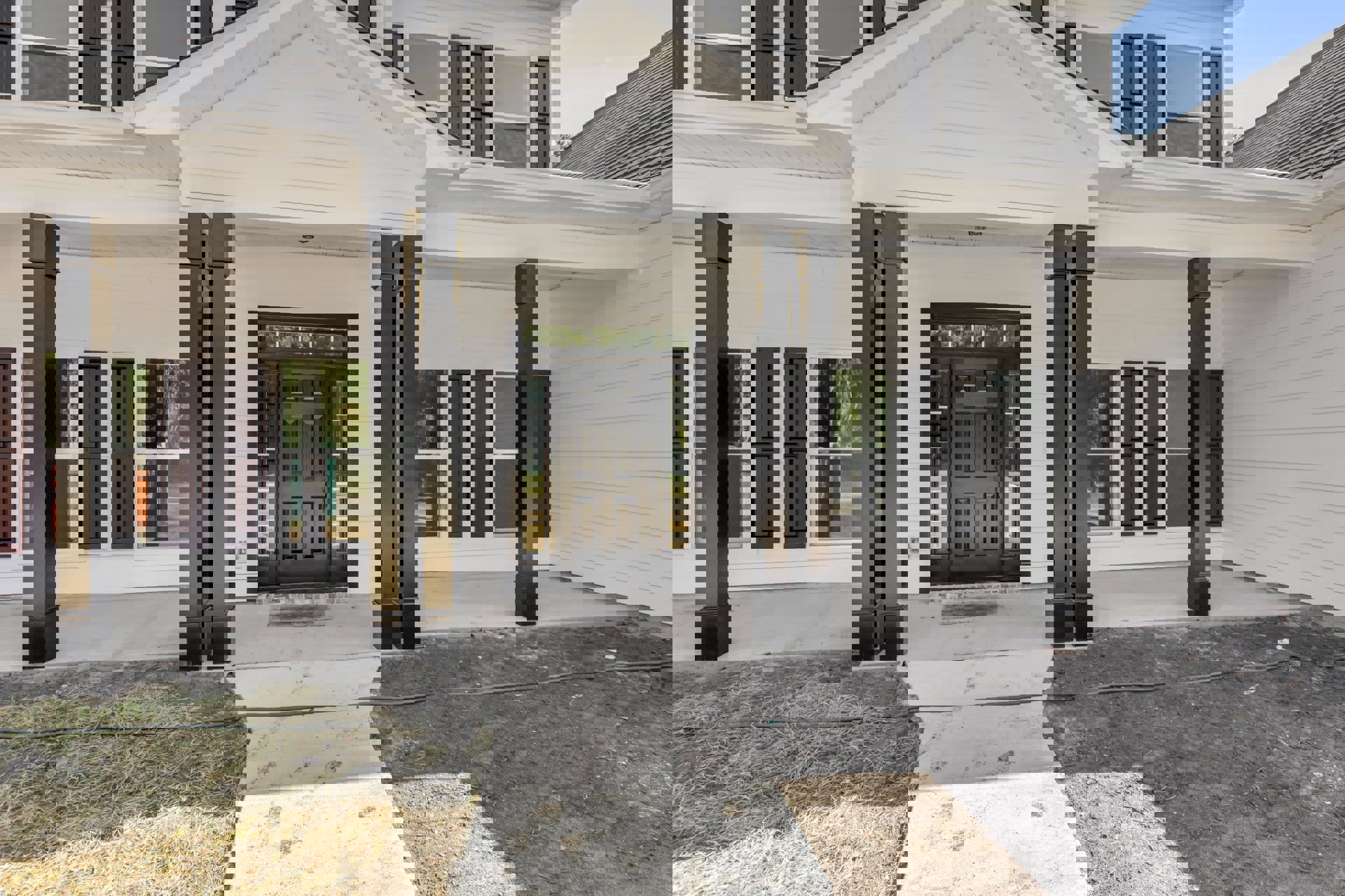 White wood-paneled exterior with black pillars, black framed glass door, and covered porch.