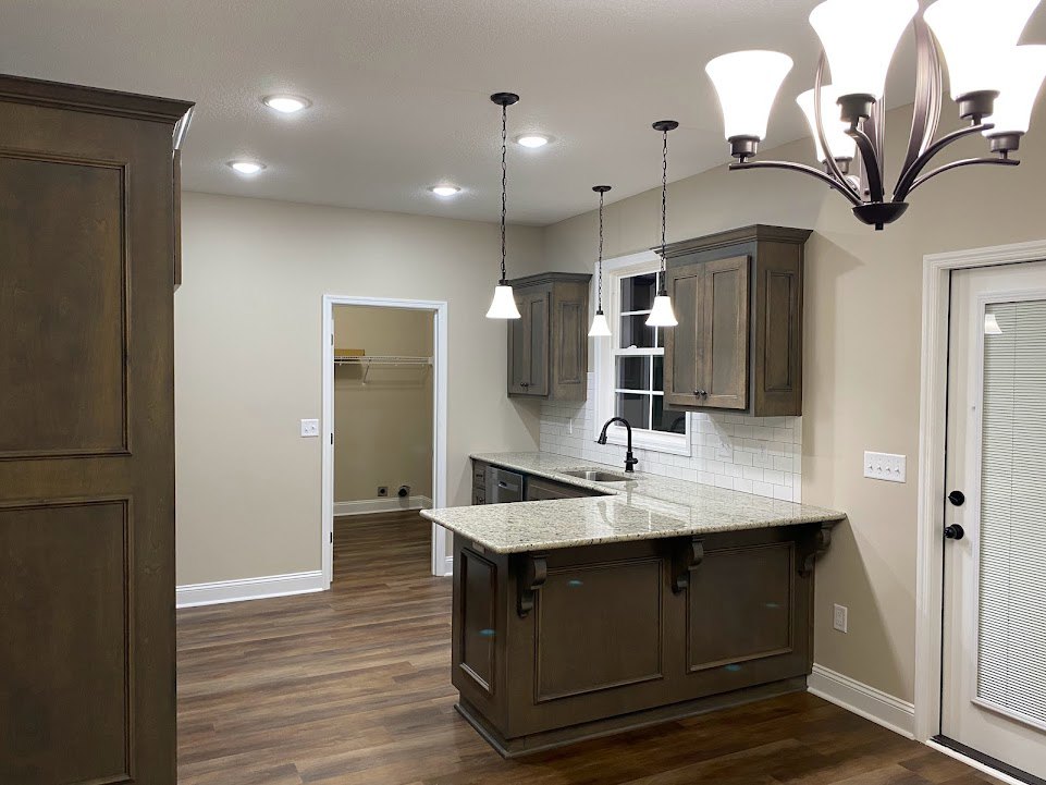 Spacious kitchen featuring a large marble-topped island, white cabinetry, tile flooring, and a modern chandelier overhead