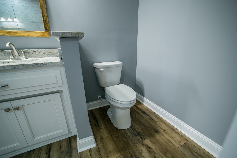 White toilet with closed lid and tank set against light tiled bathroom wall and floor.